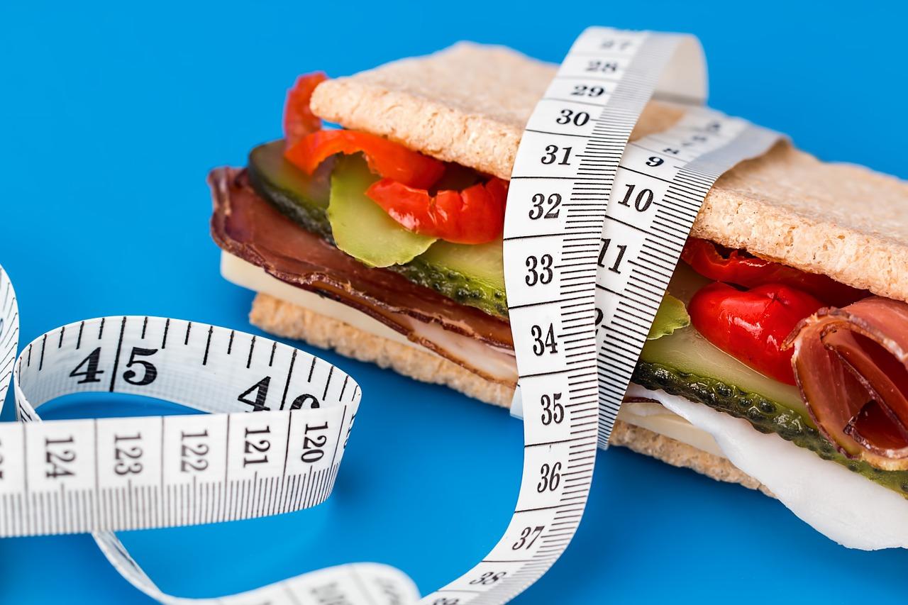 A sandwich snack with a tape measure around it. Healthy eating is part of a healthy diet.
