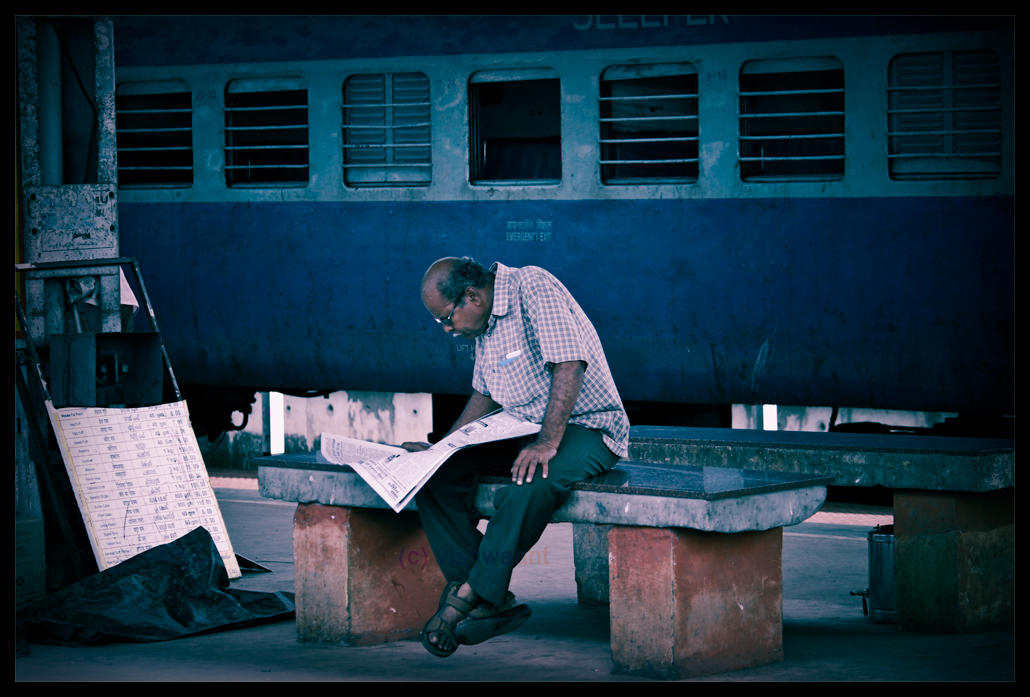 Reading Indian newpaper while waiting for the train.