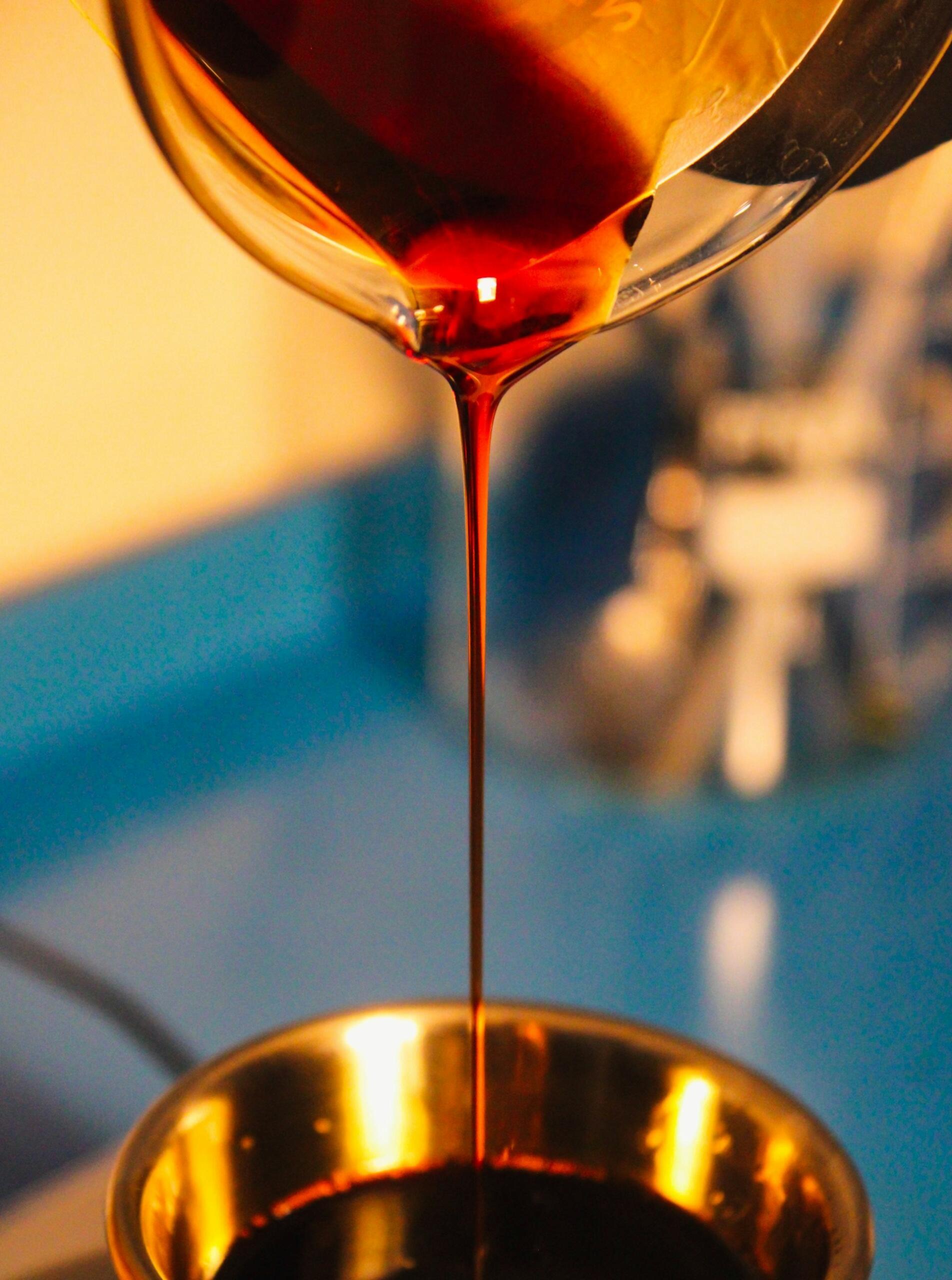 A brown liquid poured from a beaker into another vessel.