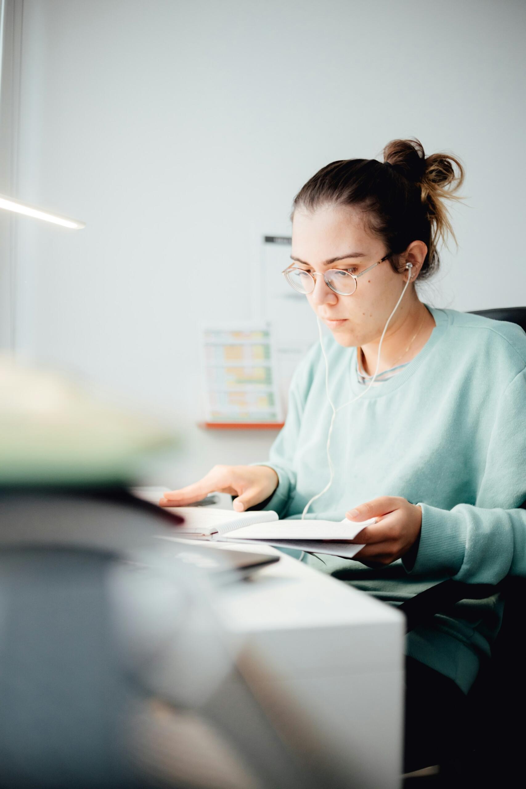 A person in a light green jumper reading a book. 