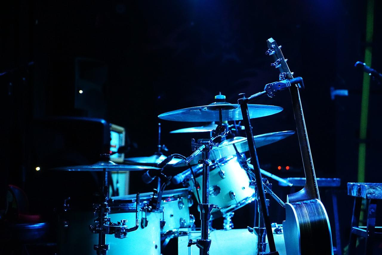 A stage with a drum set, guitar, and microphone. Drum lessons can help you get better if you play drums in a band.