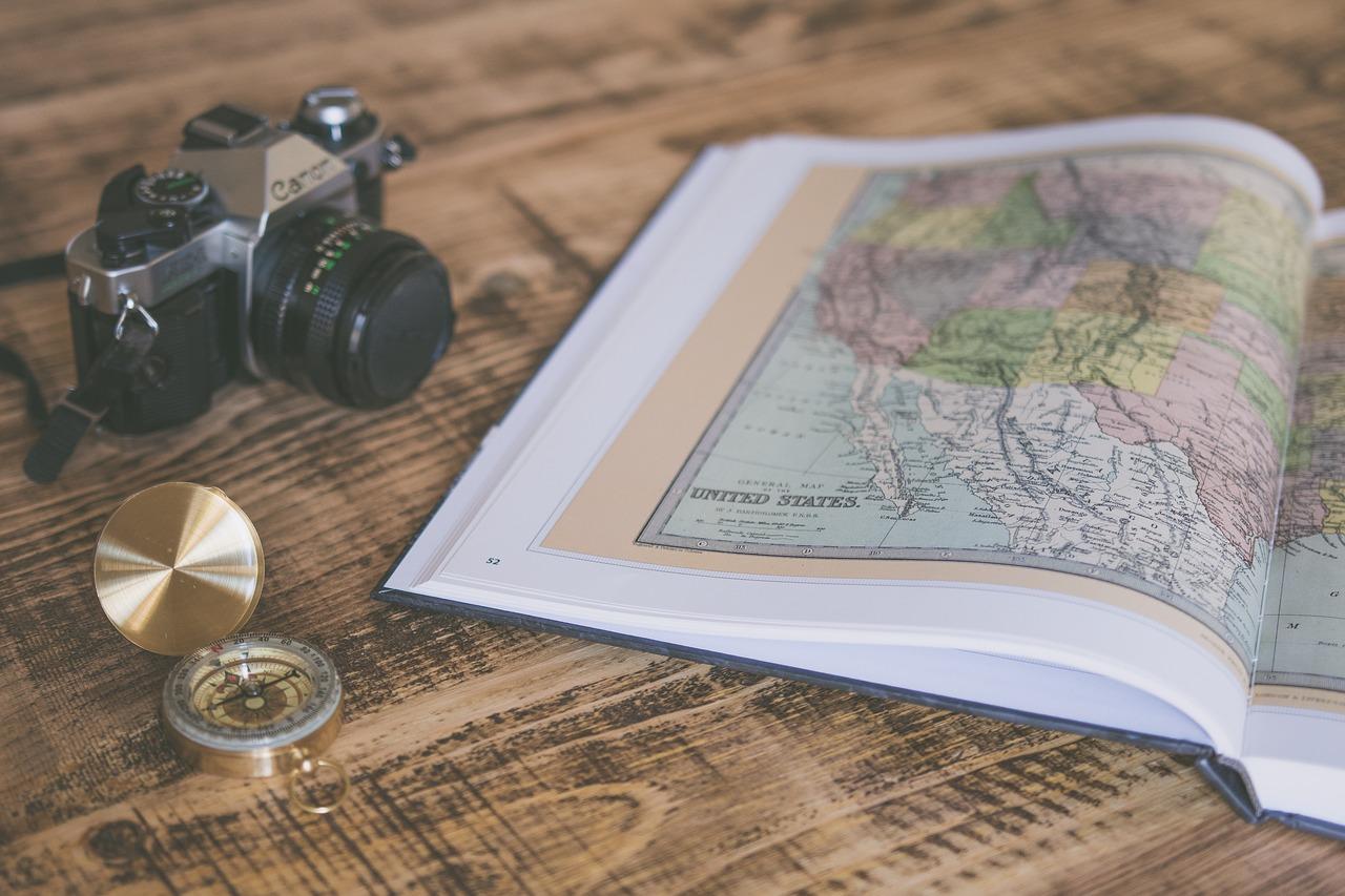 A map, a camera, and a compass on a table
