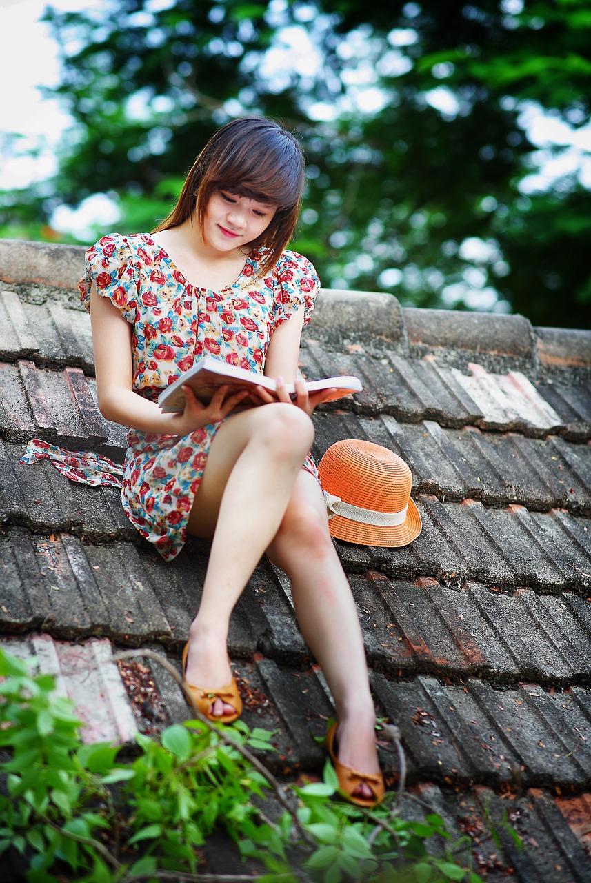 A girl reads whilst sat on a roof.