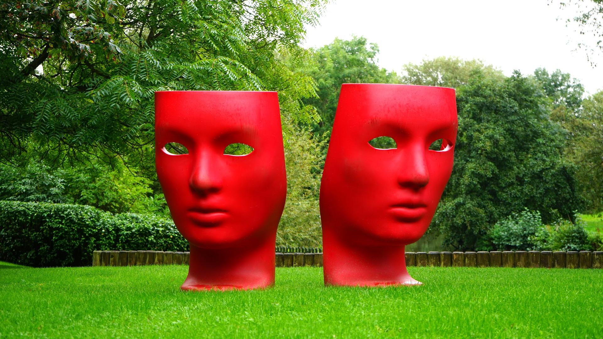A sculpture of the comedy and tragedy theatre masks, where both masks are painted red. Different acting techniques can help you when performing comedies or tragedies.