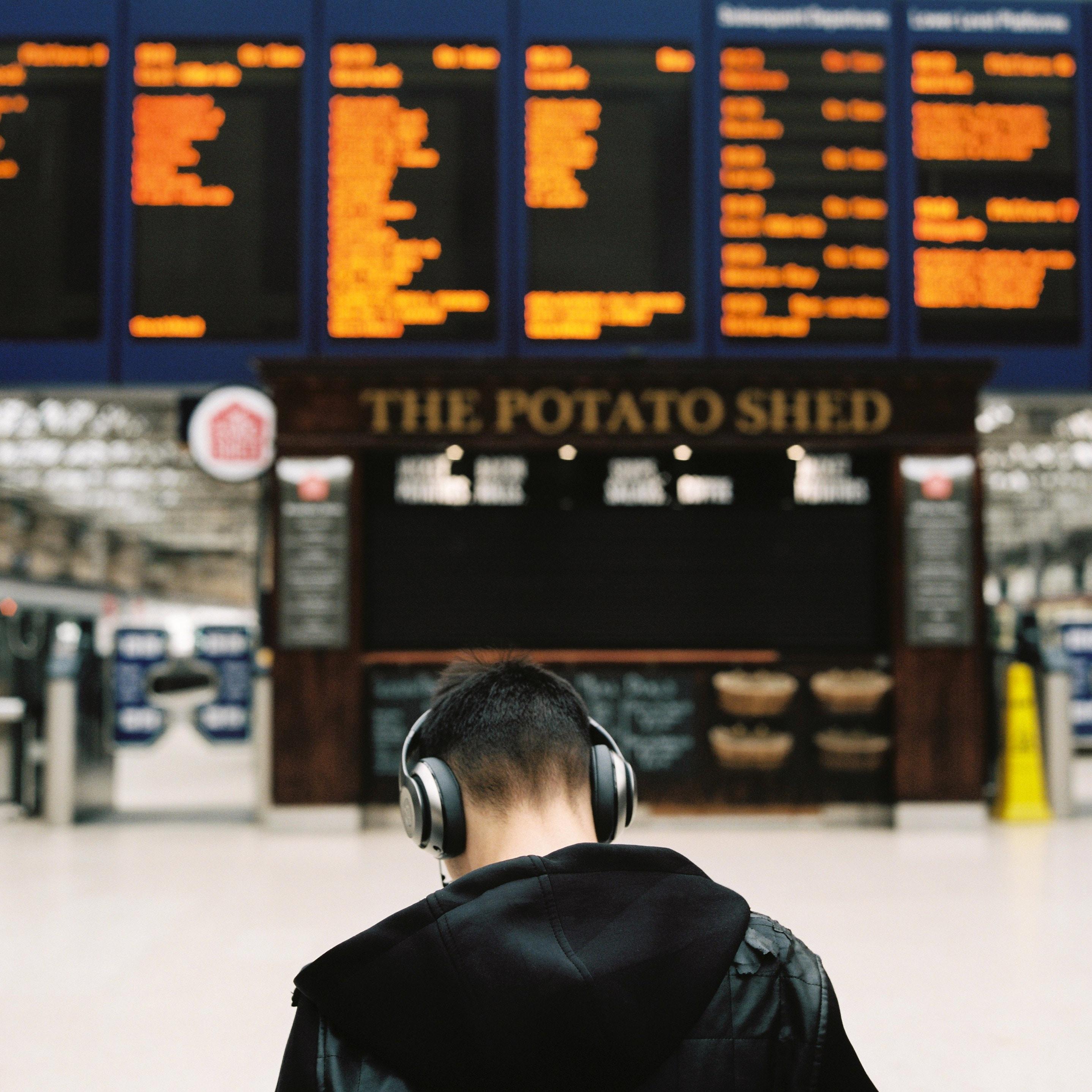 Man listens to headphones in train station.