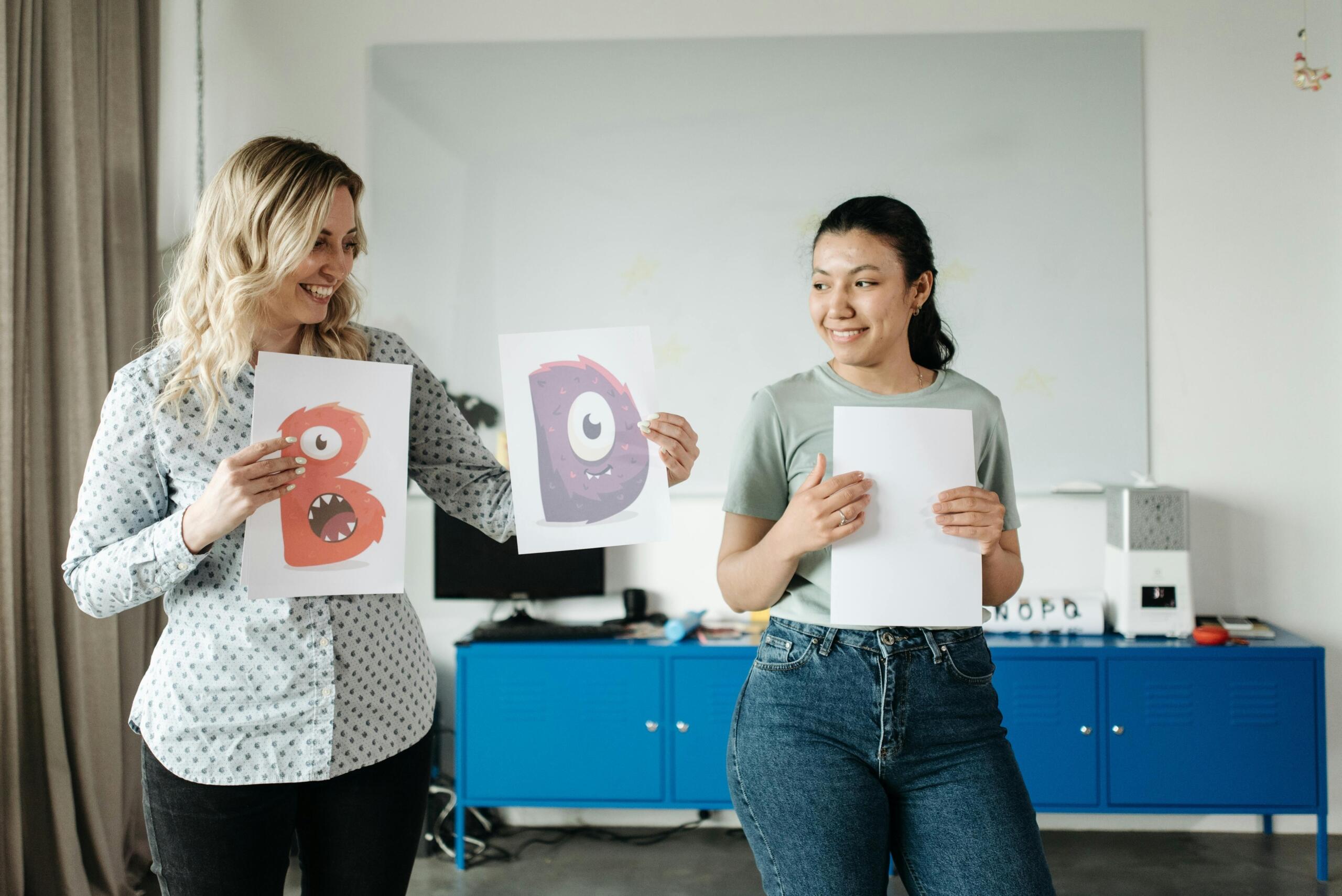 Women holding papers with art letters.