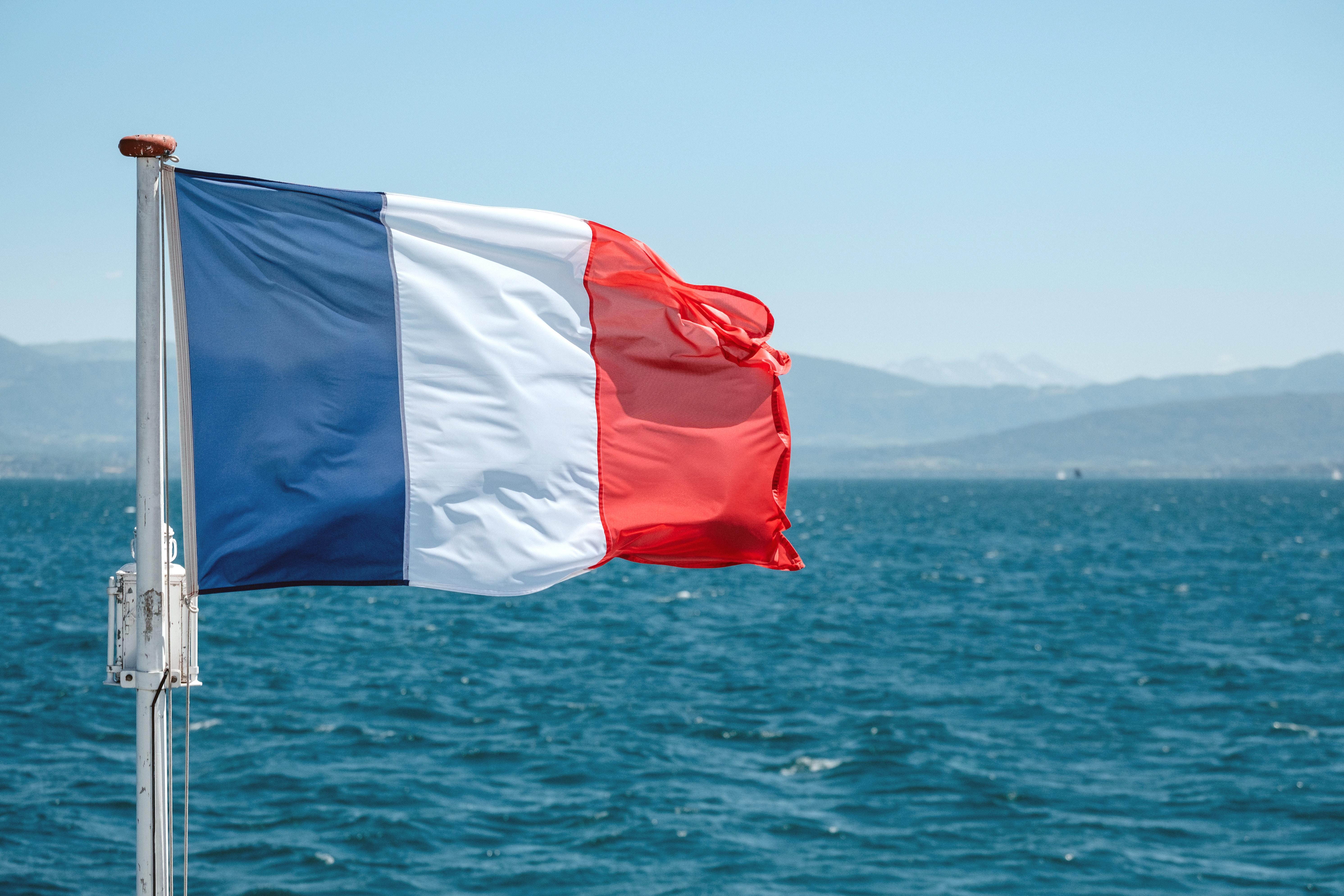 French flag blowing in front of the sea.