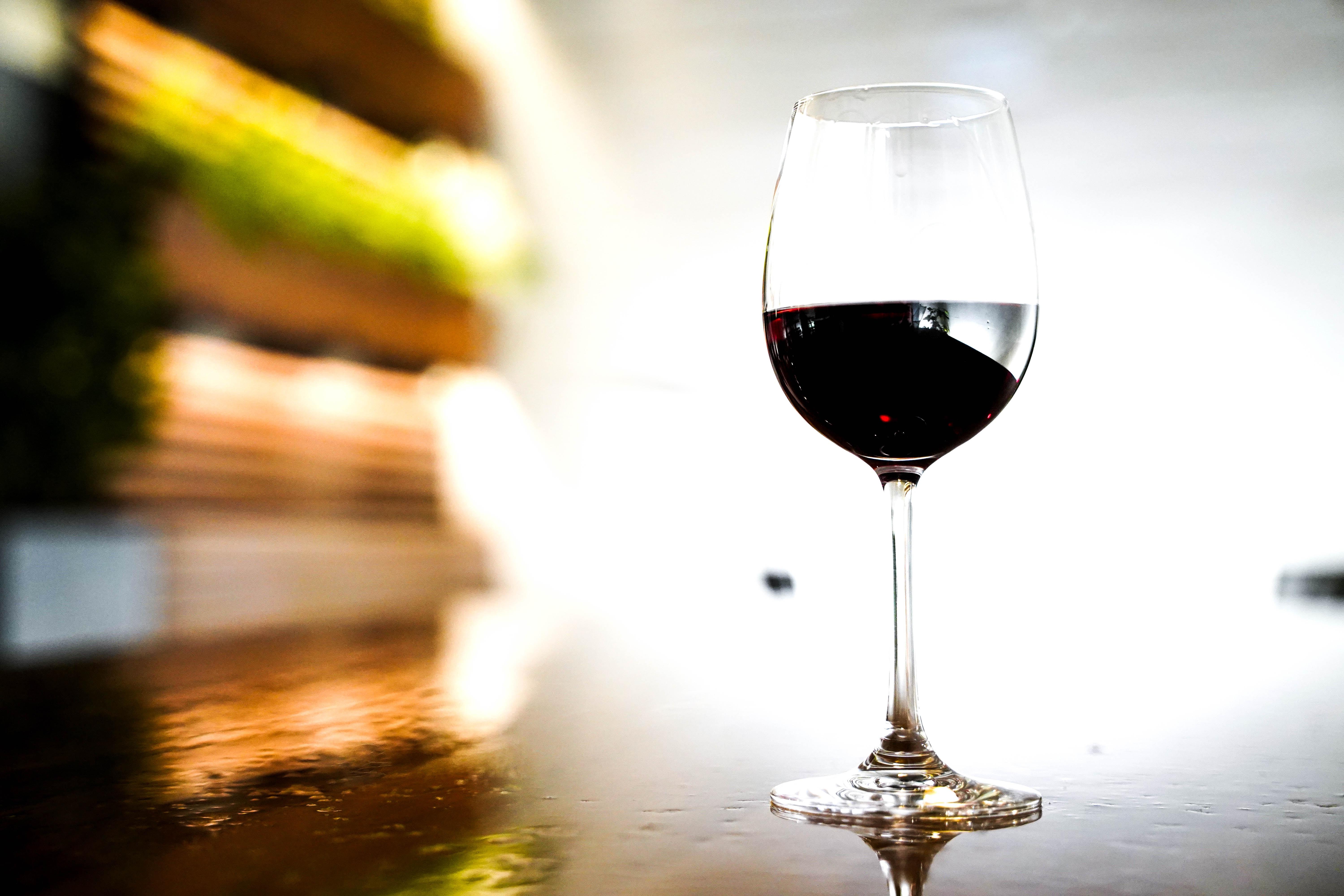 a glass of wine next to a pile of books