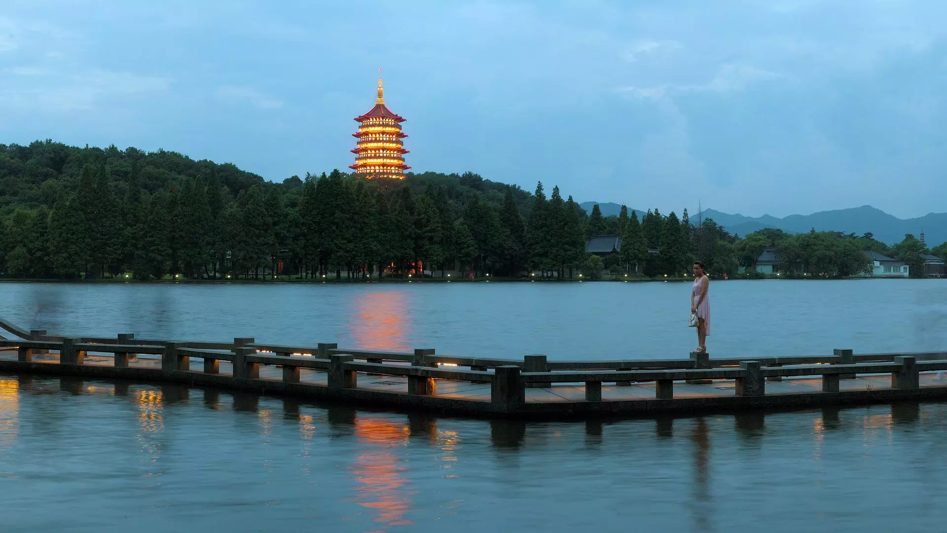 landscape view of Hangzhou, a lit building overlooking a lake in the evening