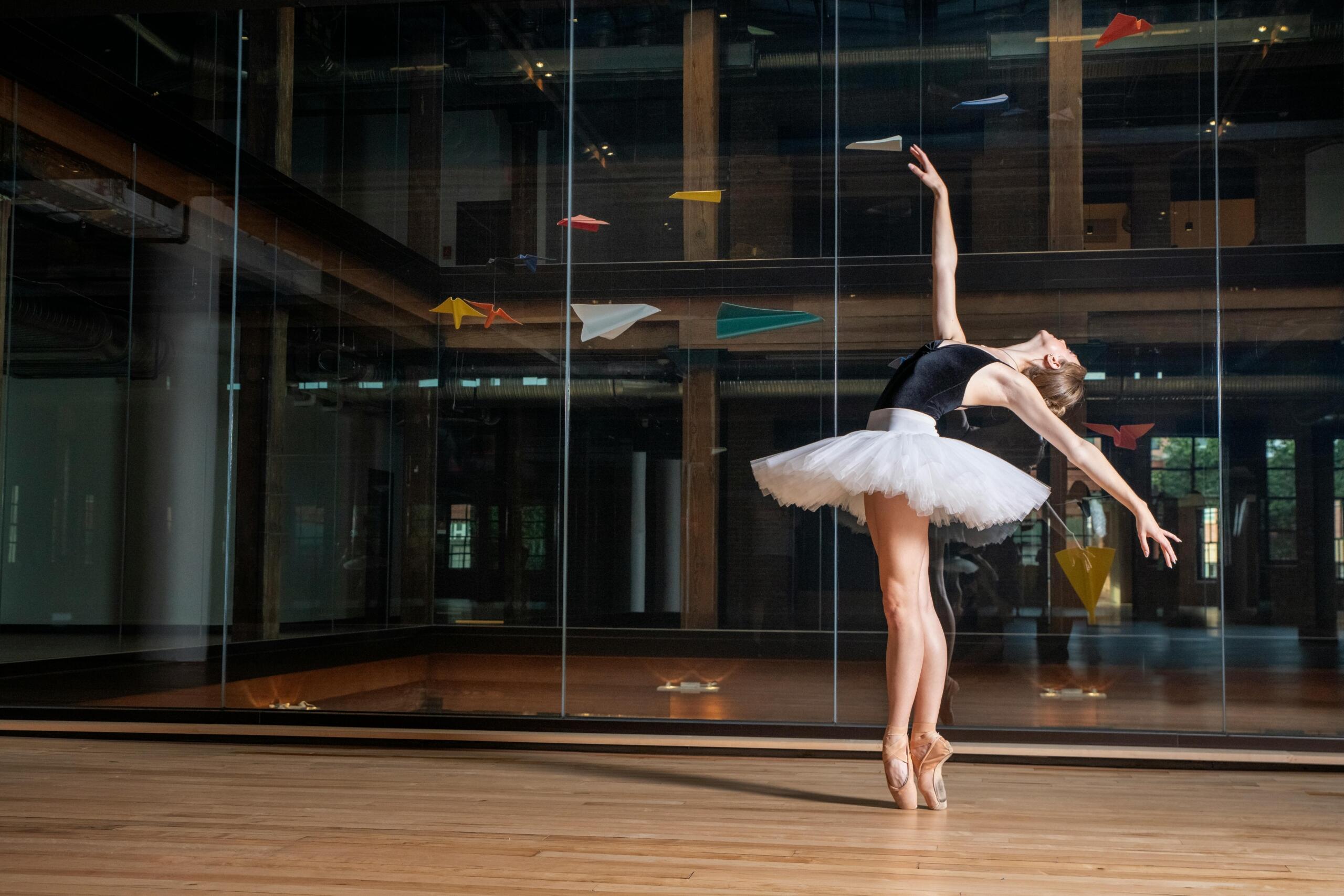 Elegant ballerina dancing in a modern indoor setting.