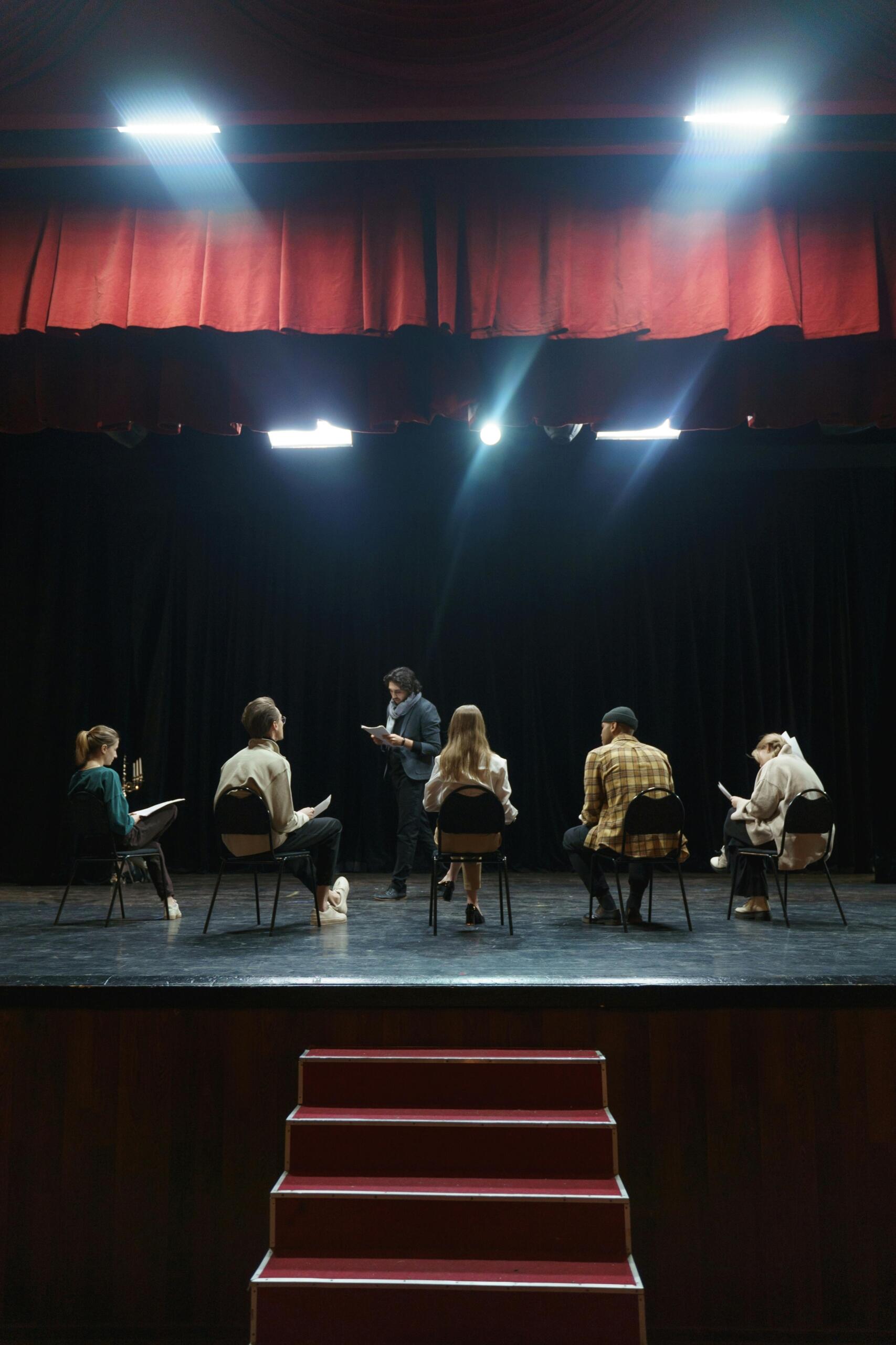 Group of people sitting on chairs on stage during a performance.