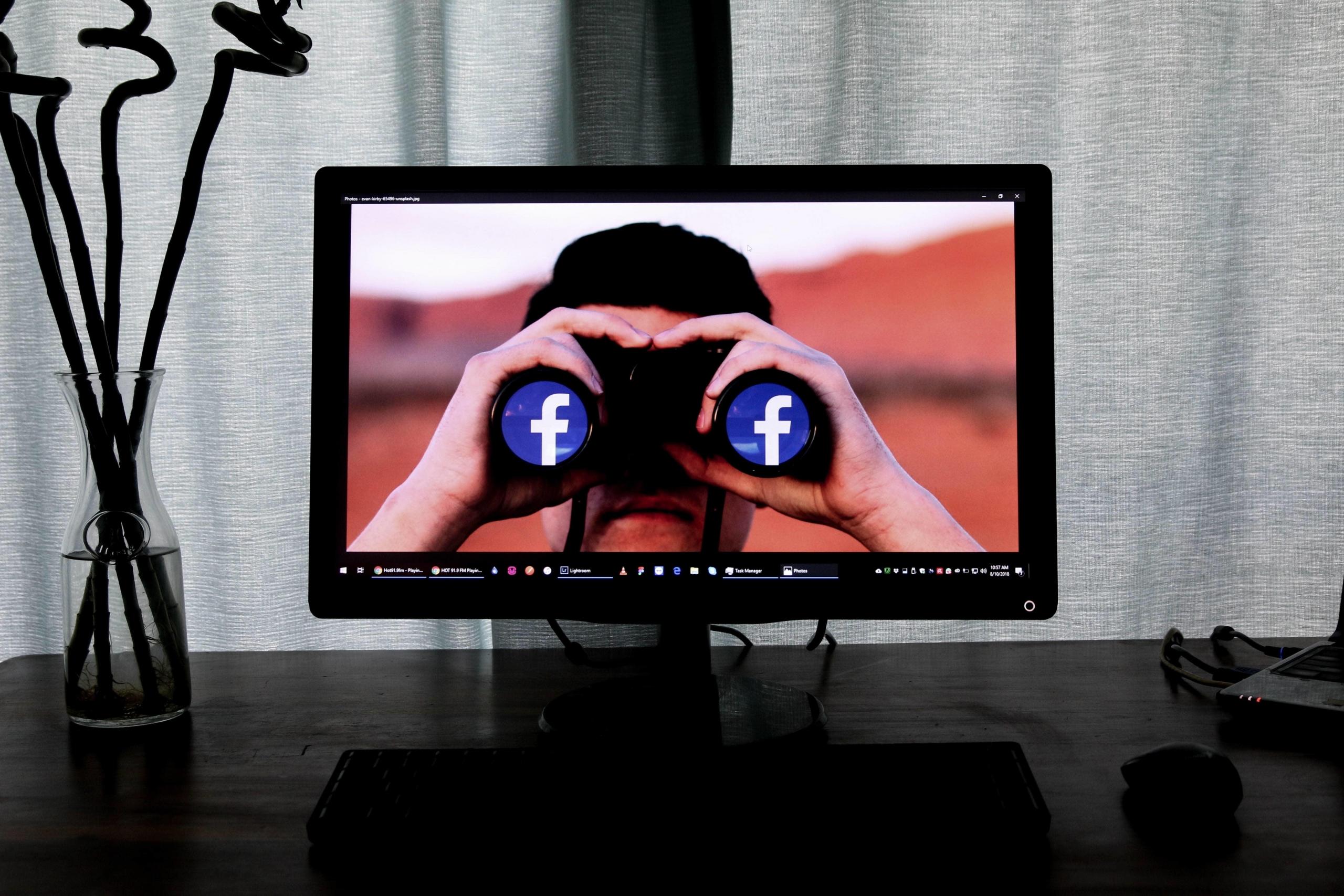 Man looking through binoculars with Facebook logo.