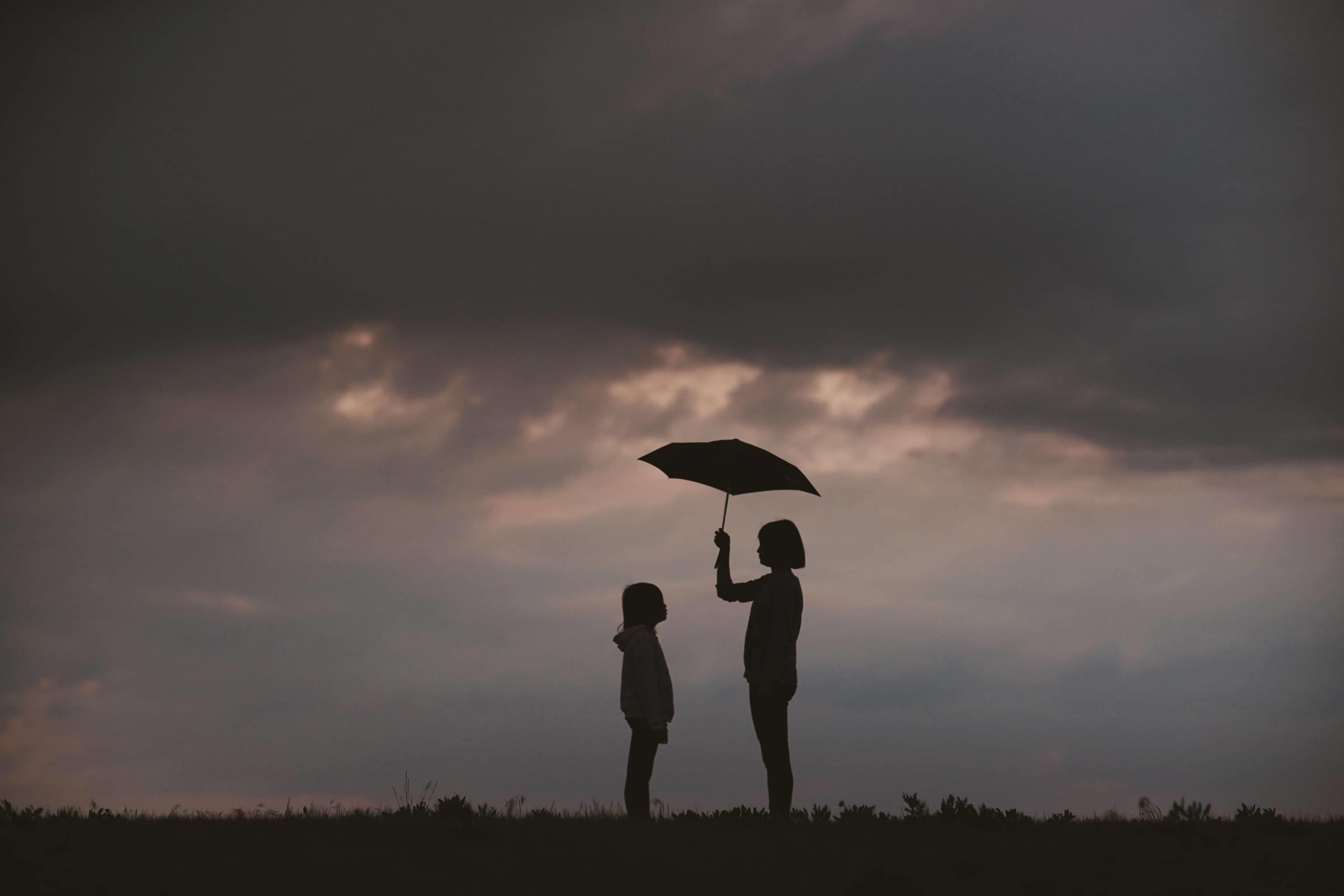 Adult and child with an umbrella.