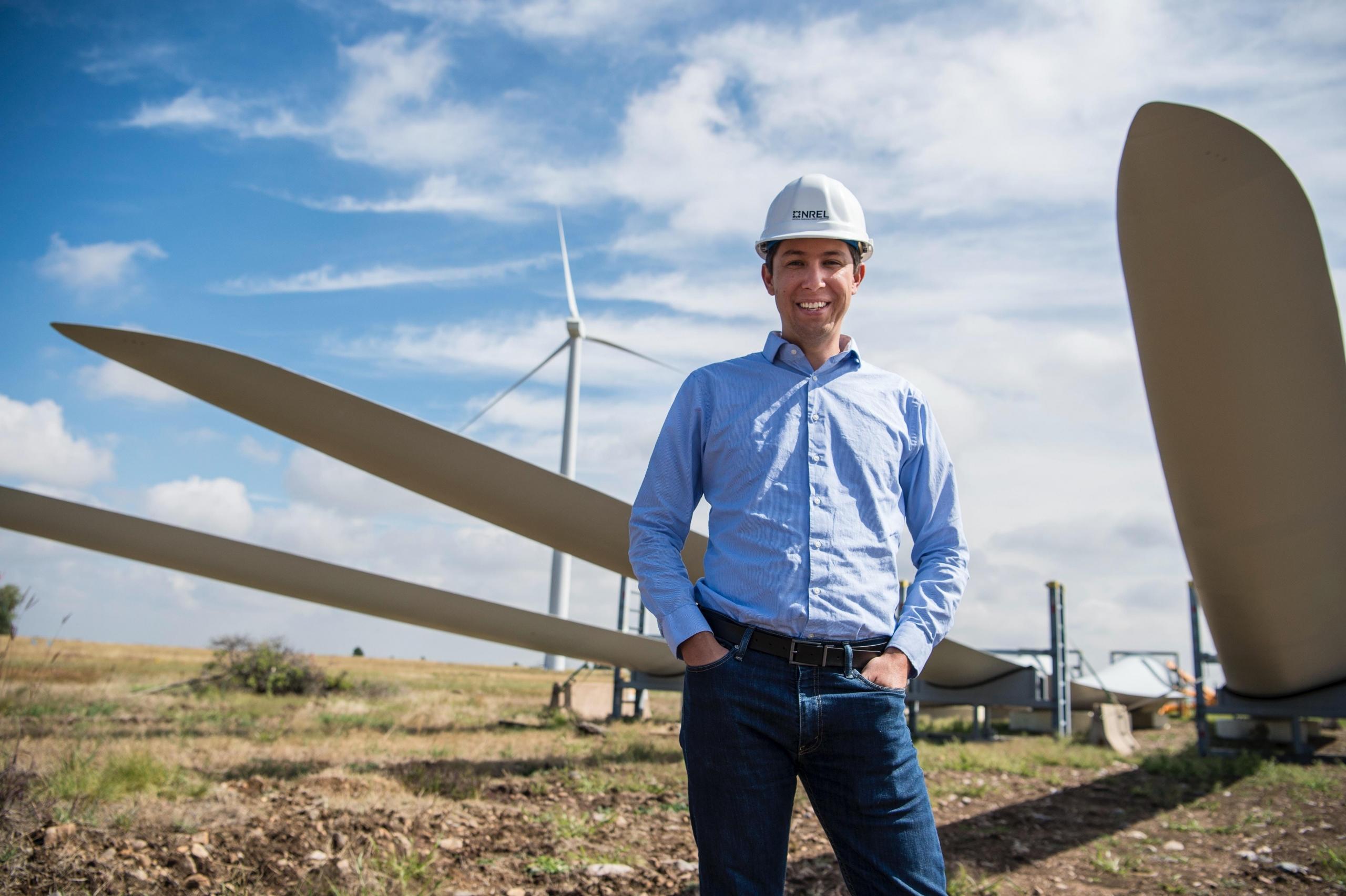 Man standing in front of wind turbine.