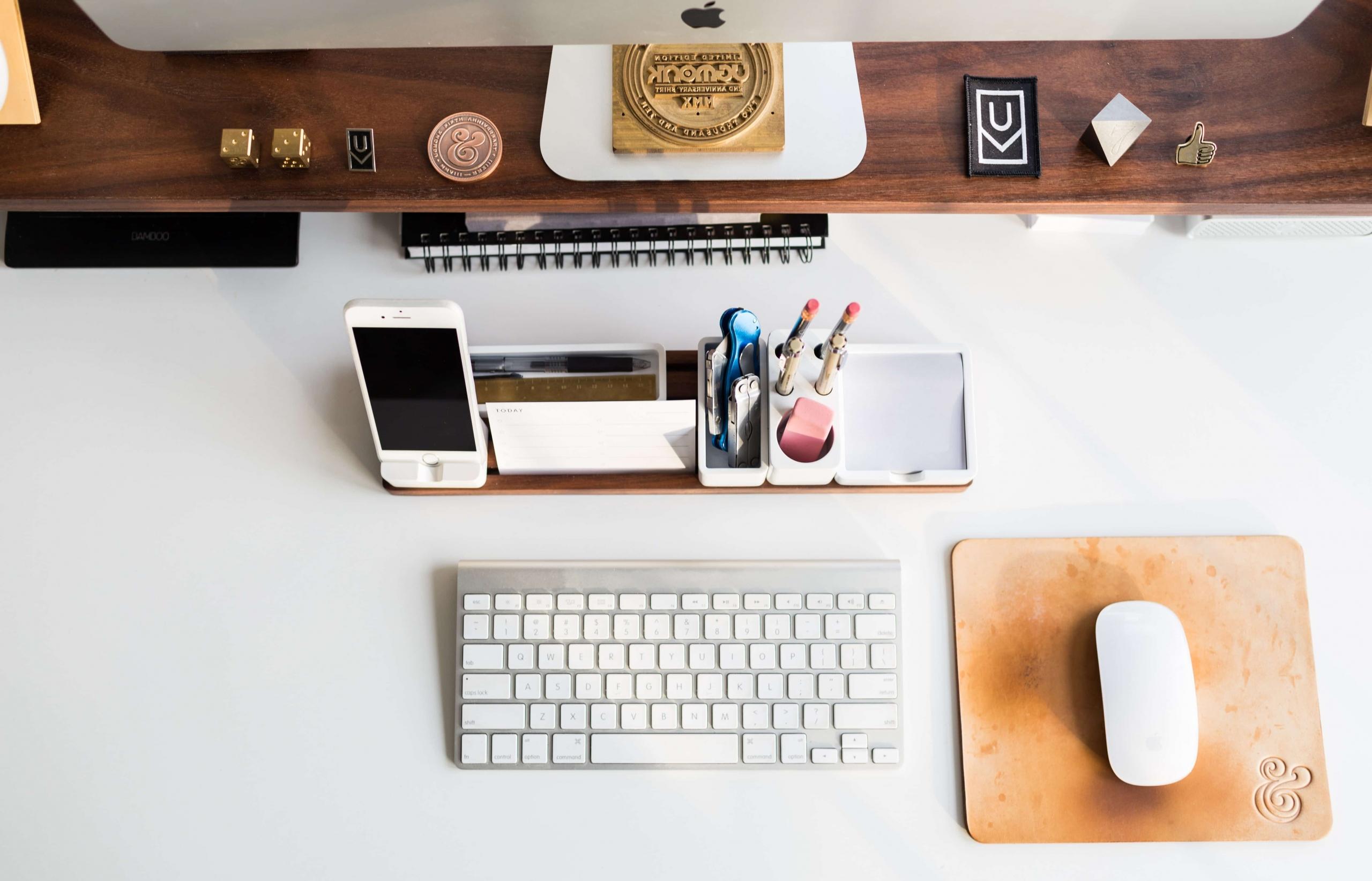 An overhead view of an orderly workspace with a keyboard, a pen caddy and a mobile visible