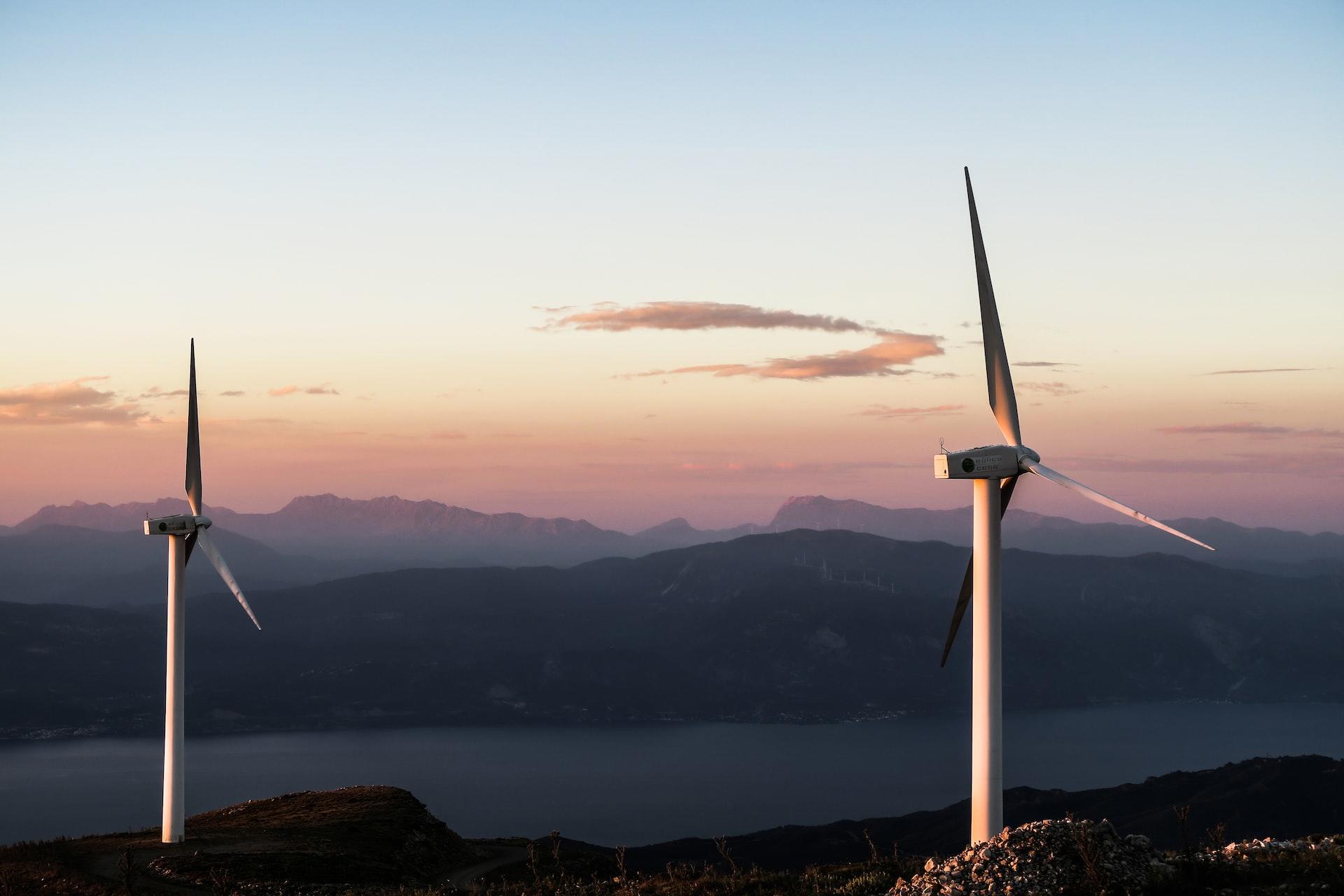 Two wind turbines set against a purpling, evening sky