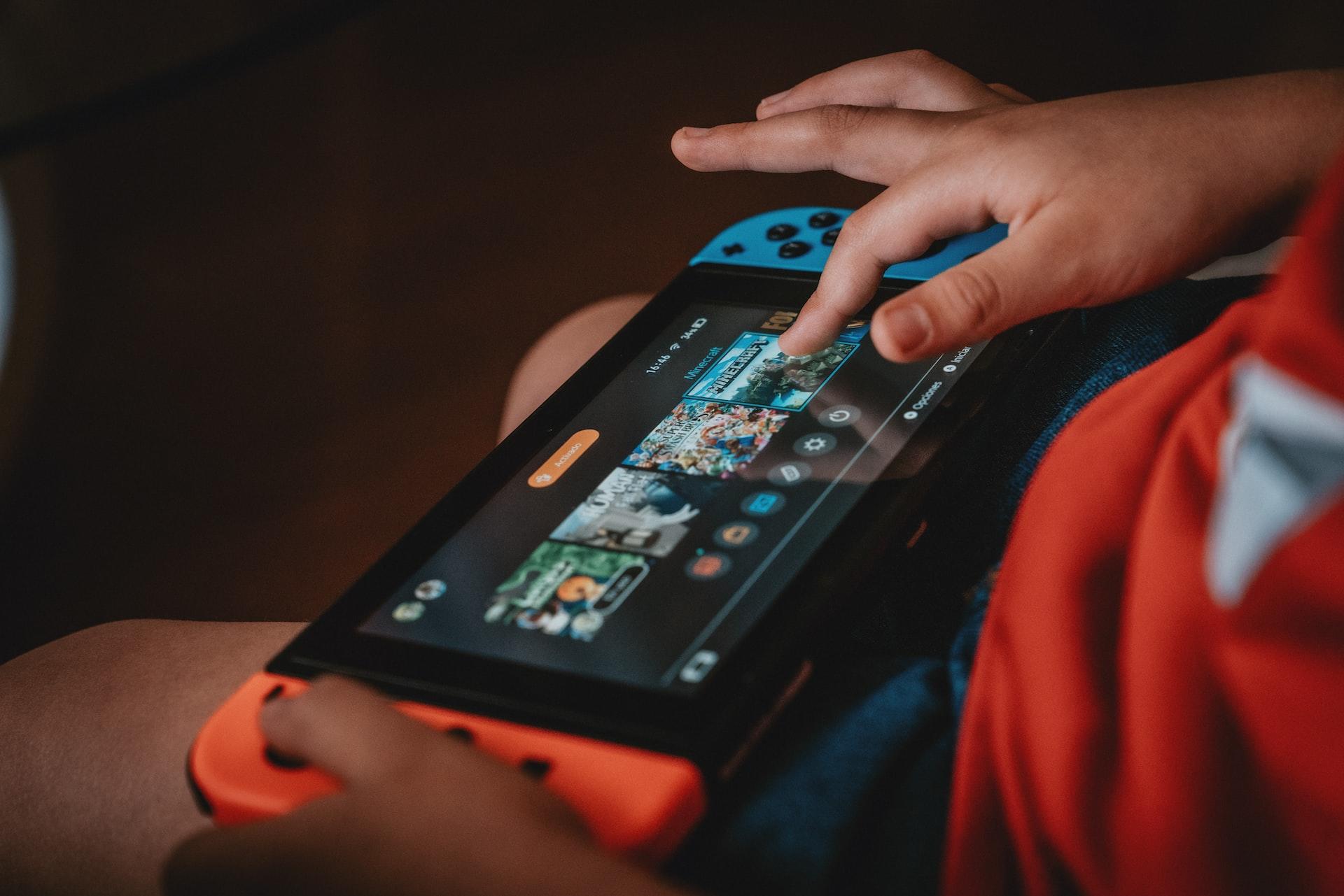 A child with a Switch in their lap fingering the device's screen. 