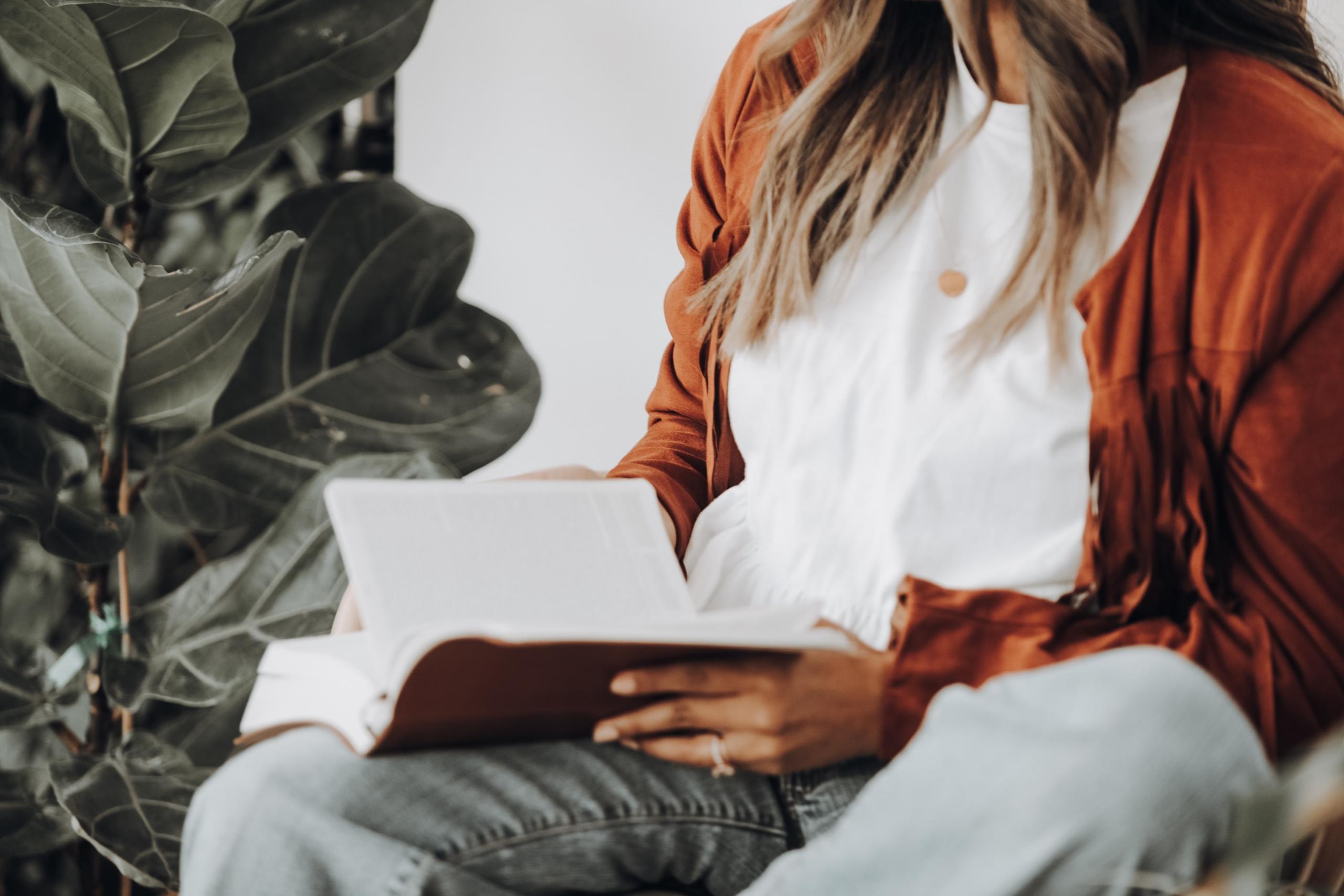 Girl reading a book next to a plant