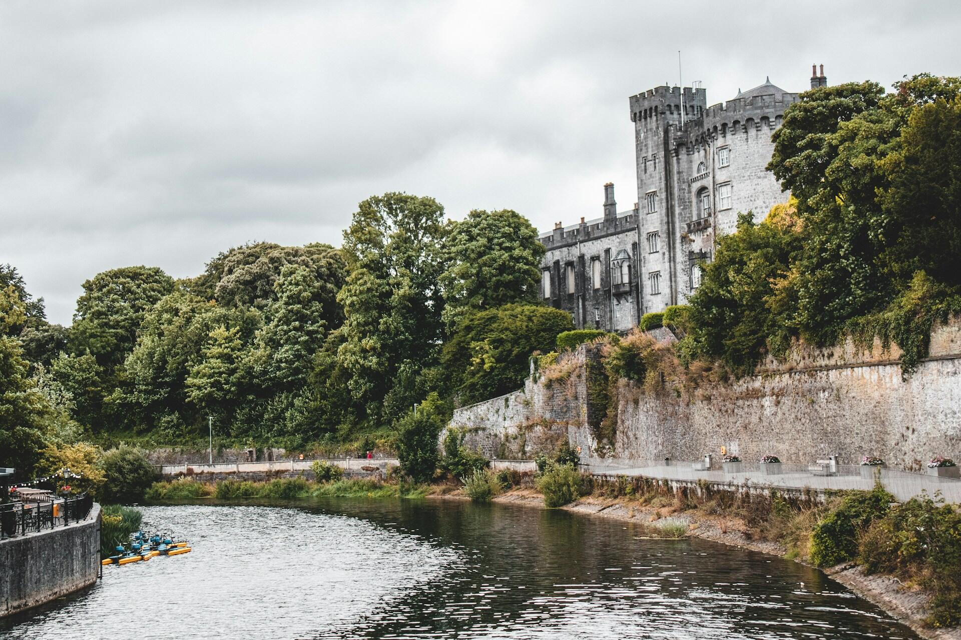 A castle overlooking a river on a cloudy day.