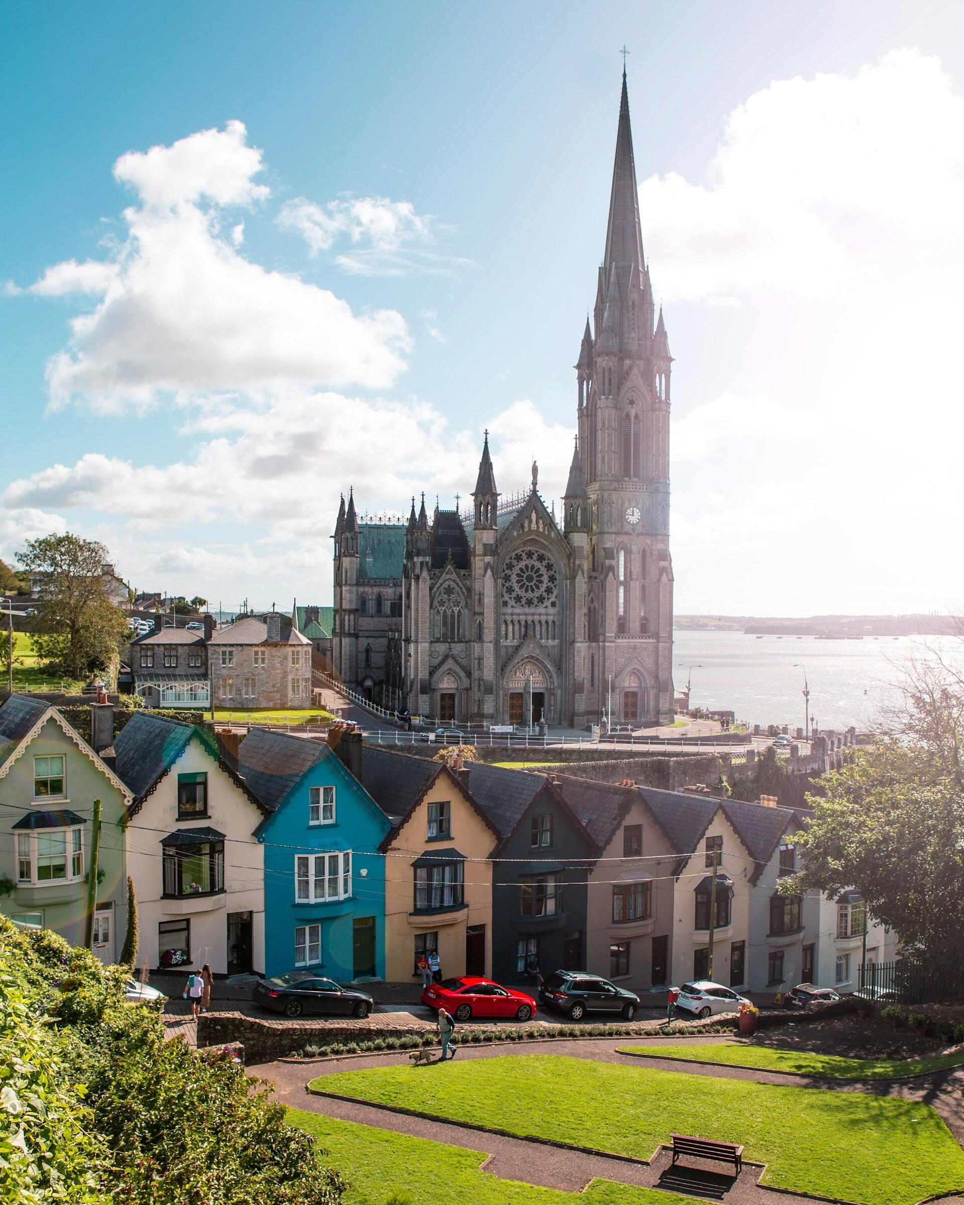 A large church behind colourful houses on a sunny day.