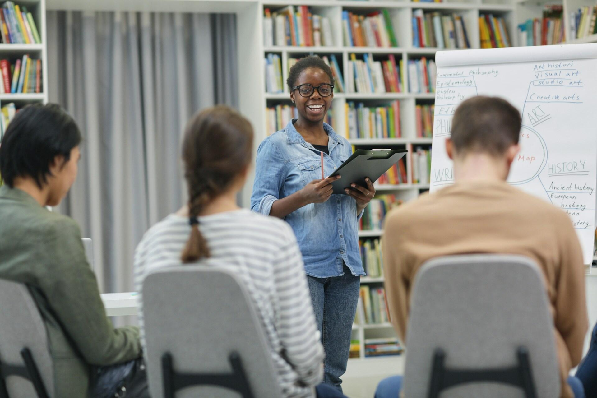 students sitting around a table during a tutorial session with a teacher at the front of the class