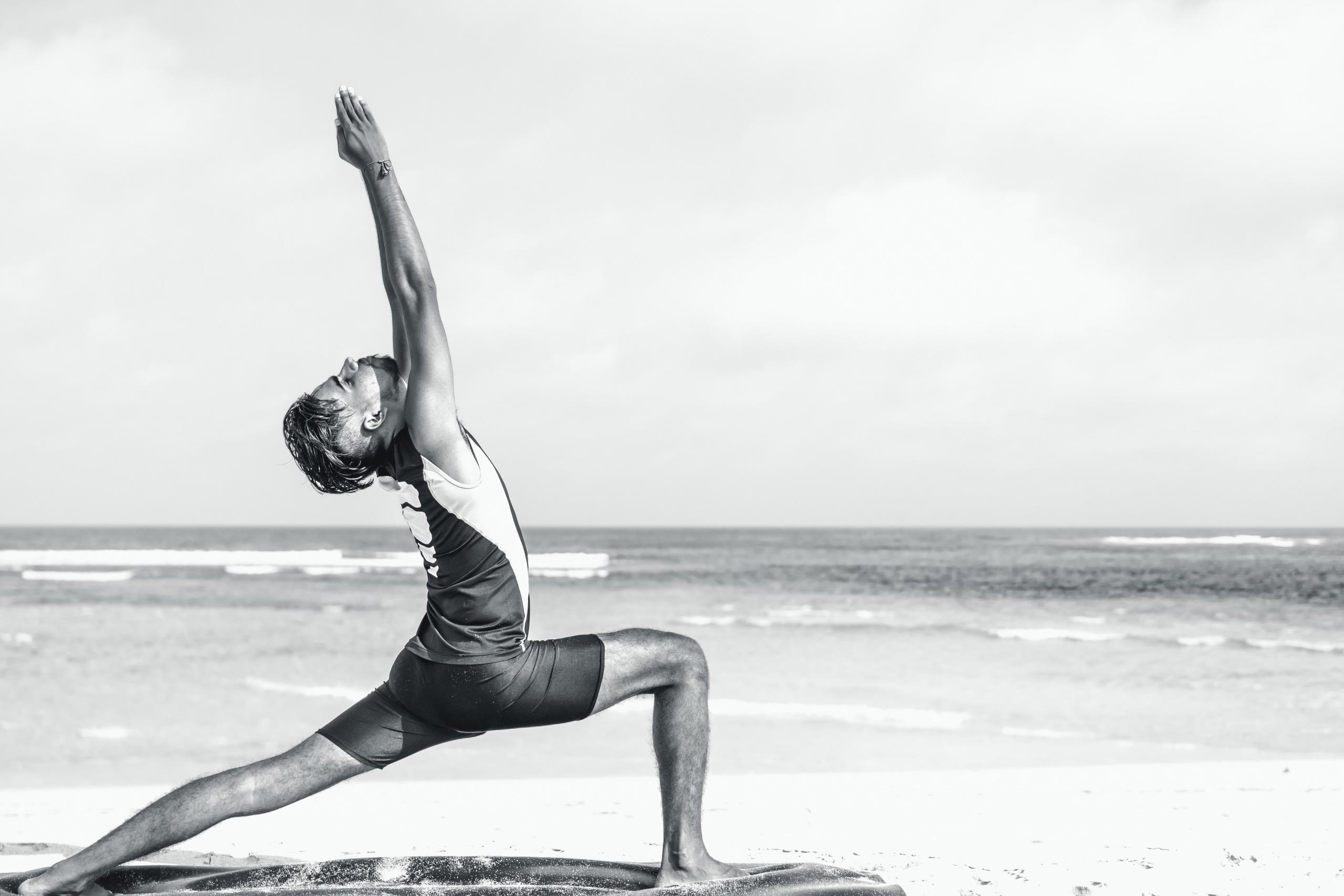 Man doing yoga on the beach