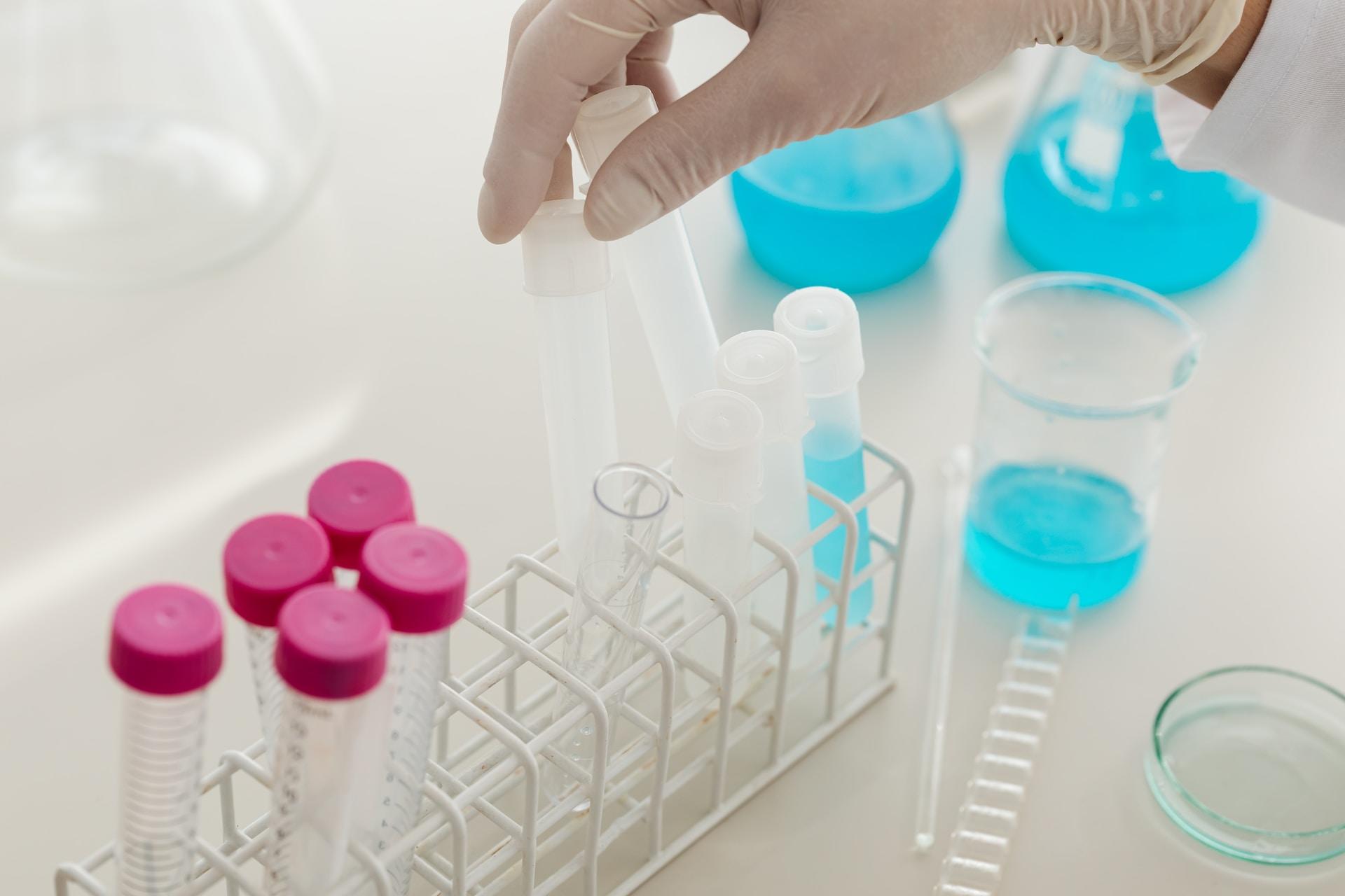 A person holds a pipette above some test tubes.