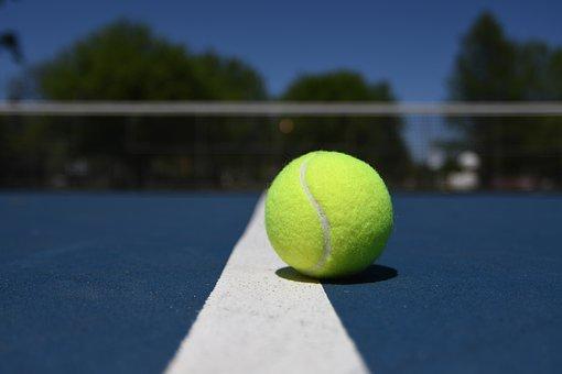 A tennis ball resting on a tennis court ground