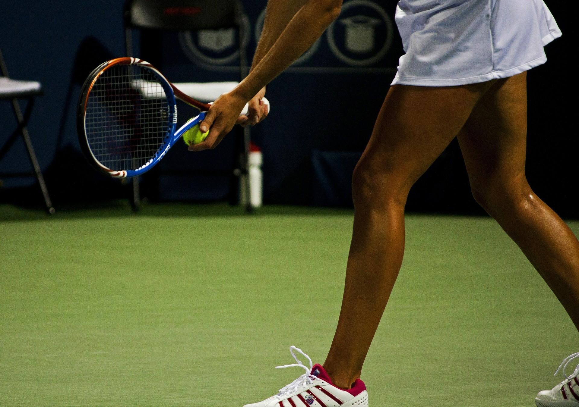 A professional tennis player readies their serve