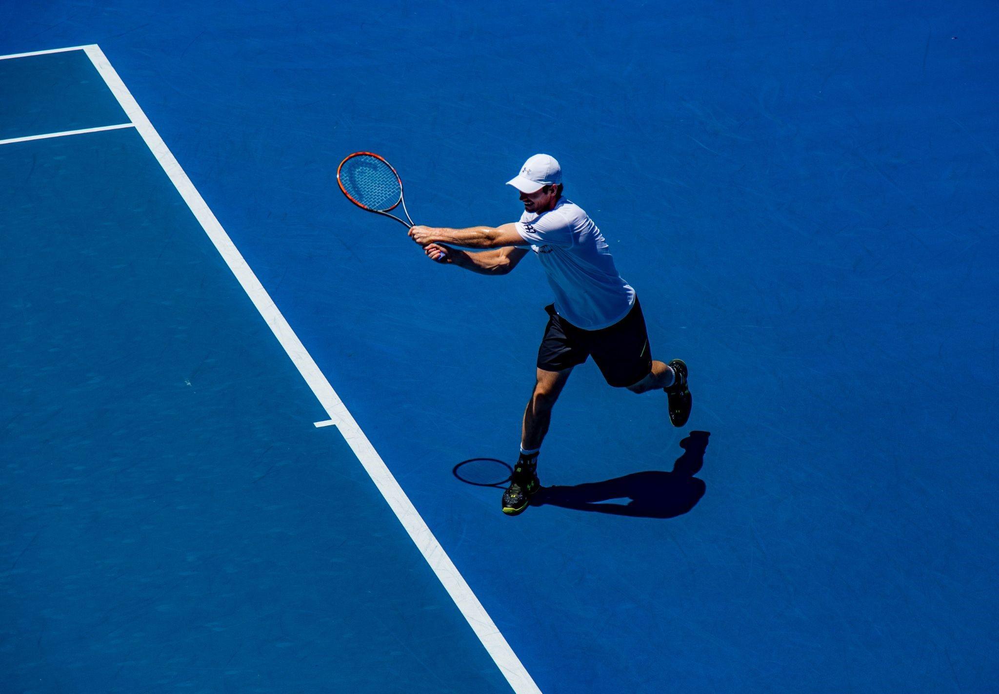 A tennis player is reaching out to hit the ball