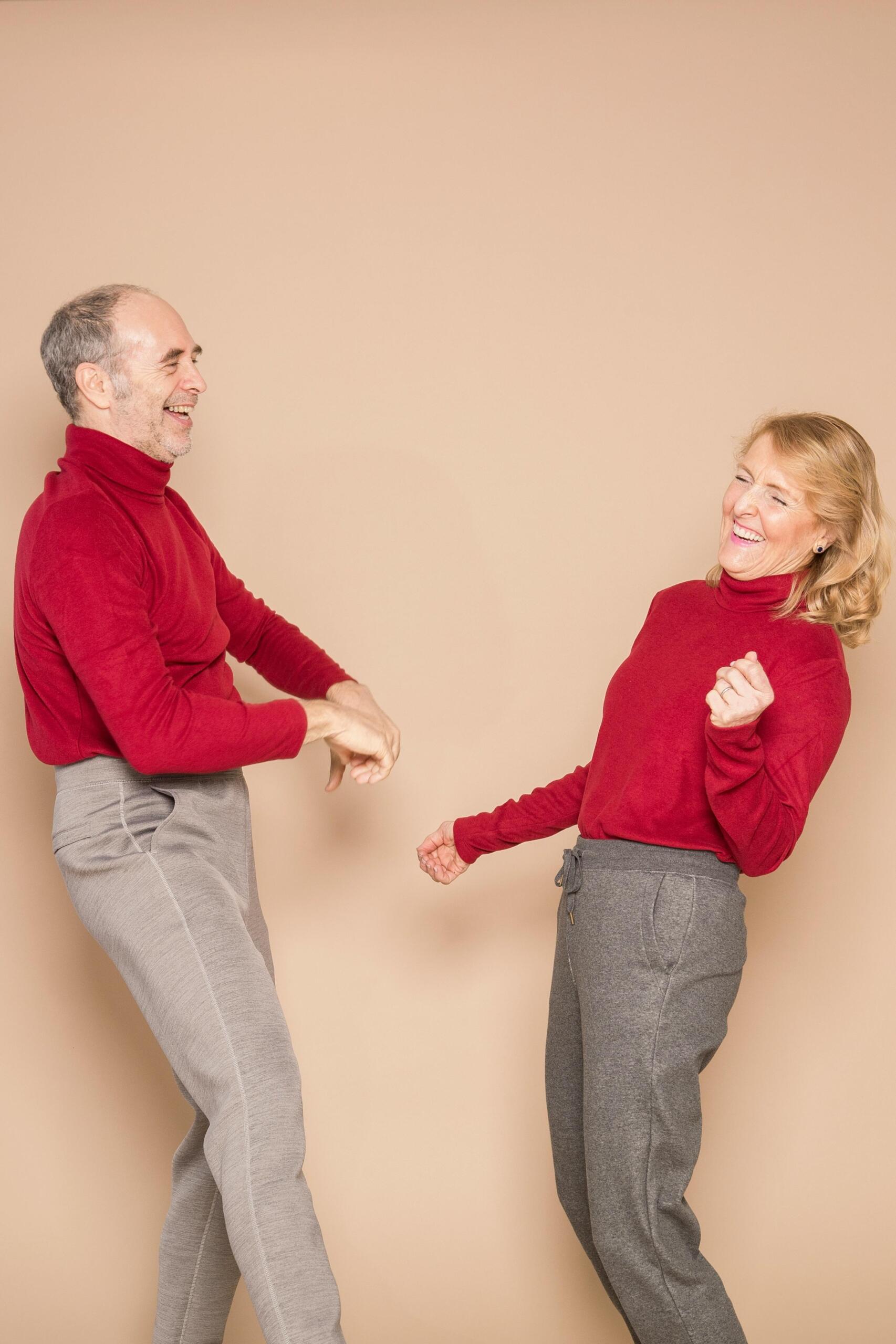 A couple wearing matching red sweaters dancing together.