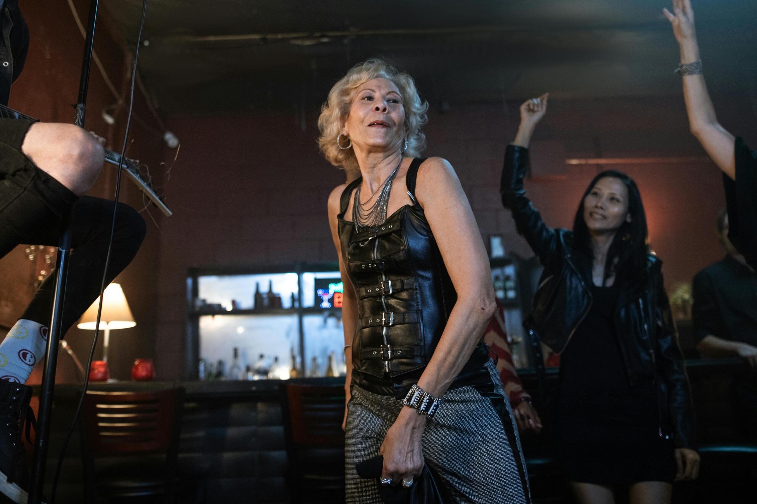 An elderly woman dancing with confidence in a club setting.
