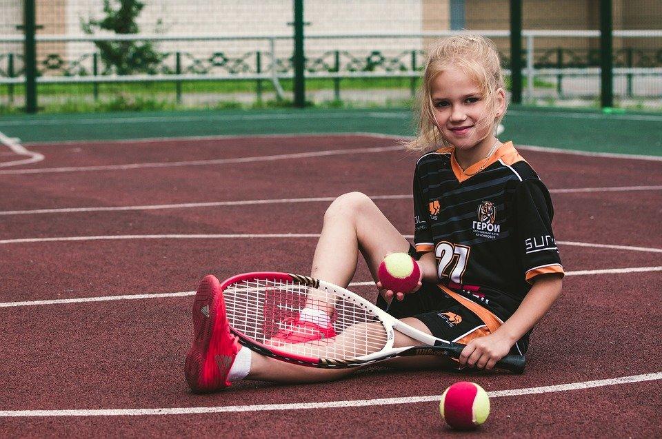 A little girl relaxes with her tennis gear