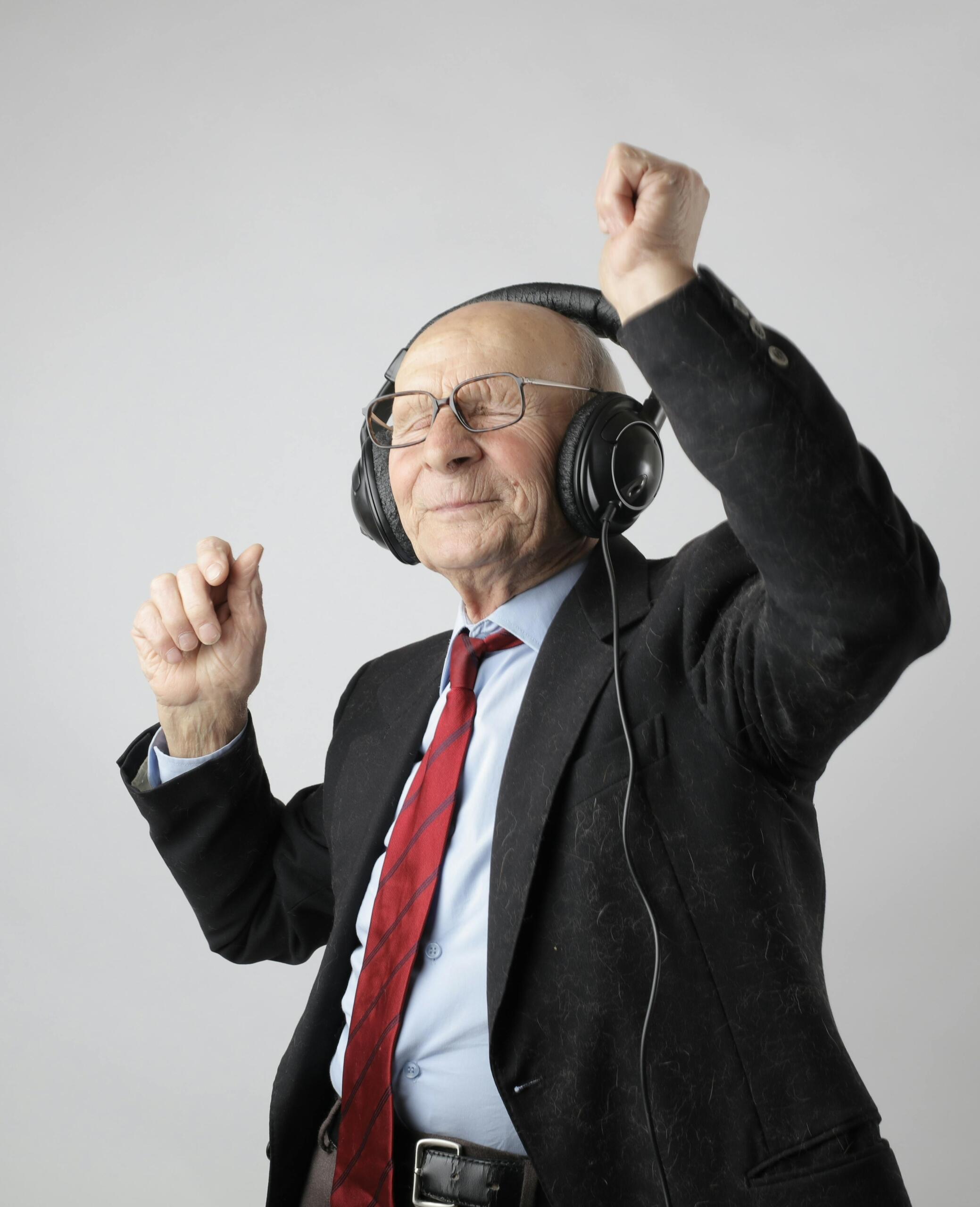 A man in a black jacket wearing headphones and dancing joyfully.
