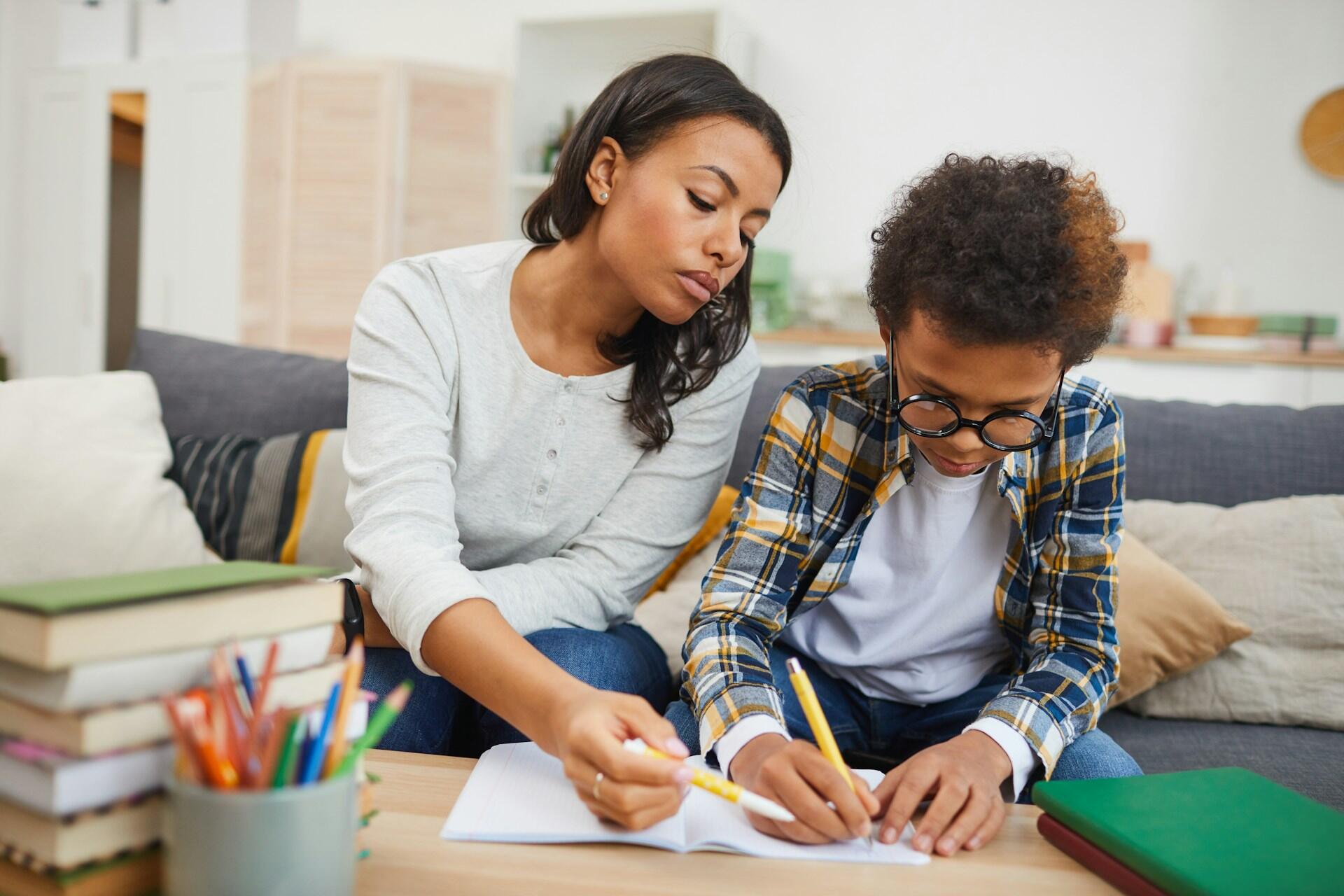 A woman monitoring a boy's writing.