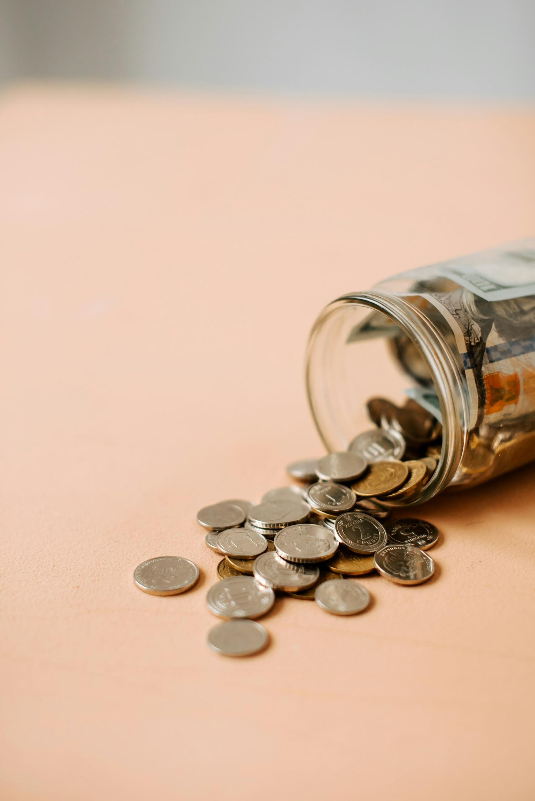 A jar of coins on its side, with a few spilled out.