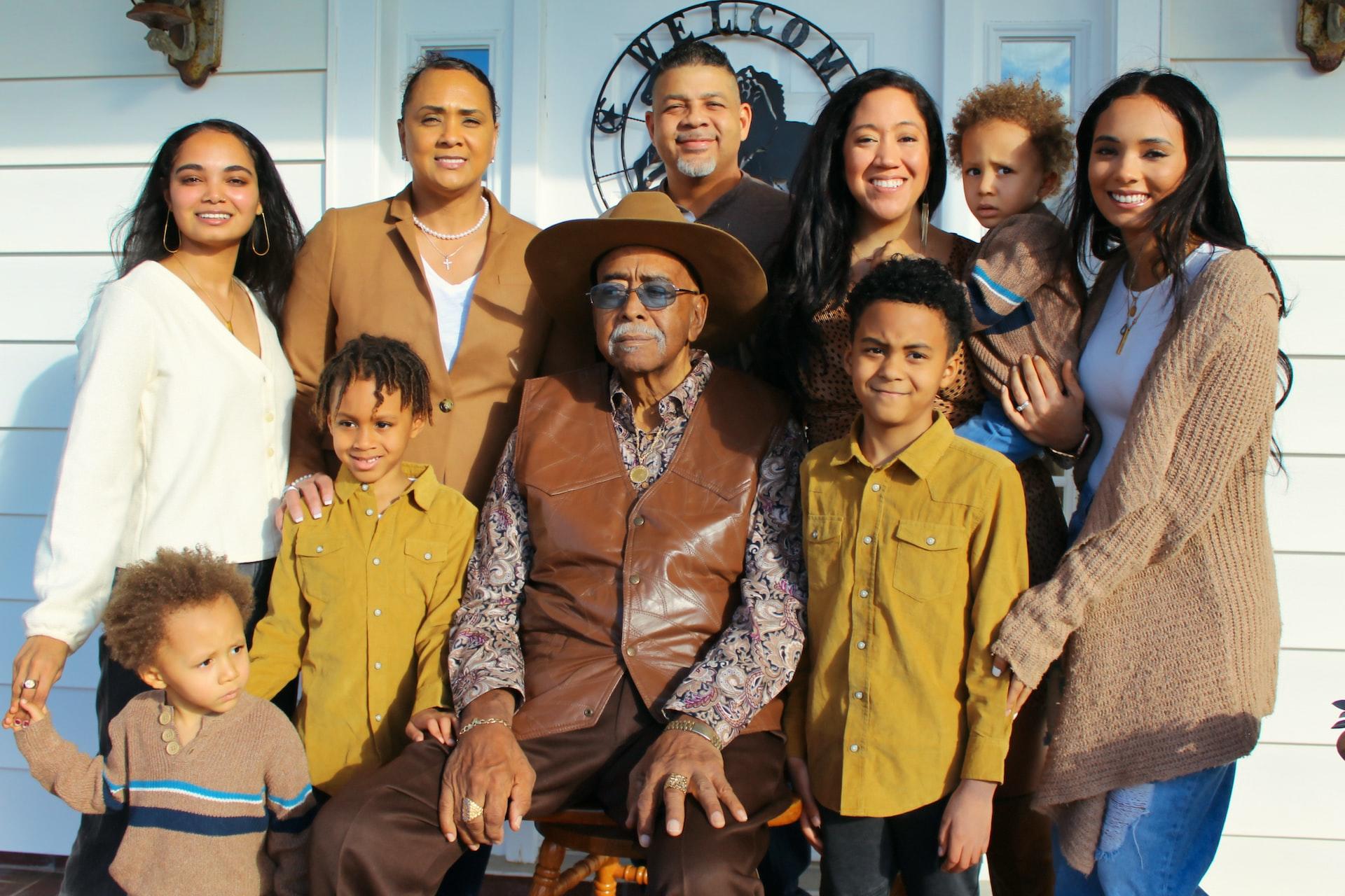 A group of 10 people wearing colour-coordinated clothing pose in front of a house