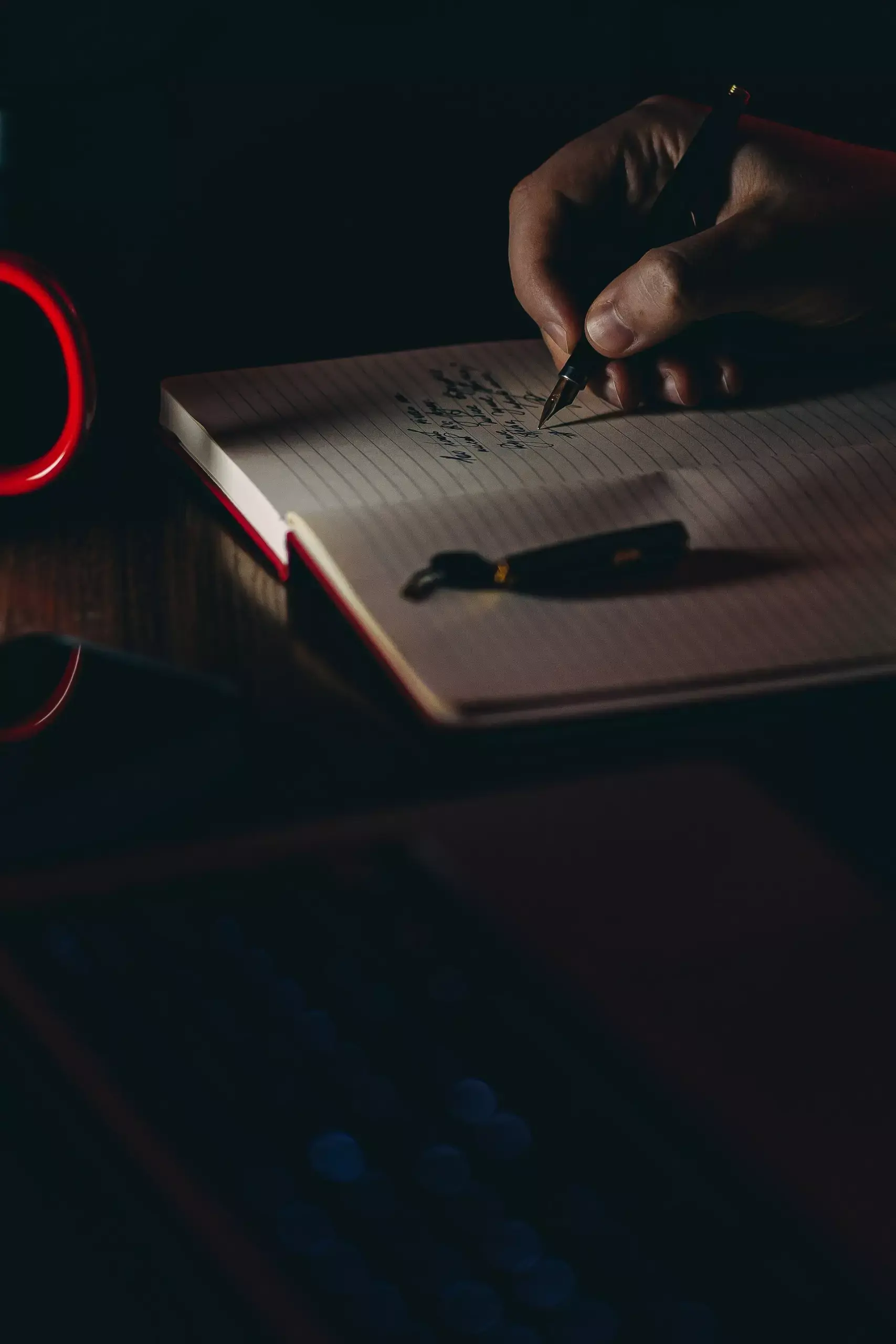 person writing in a notebook in the dark
