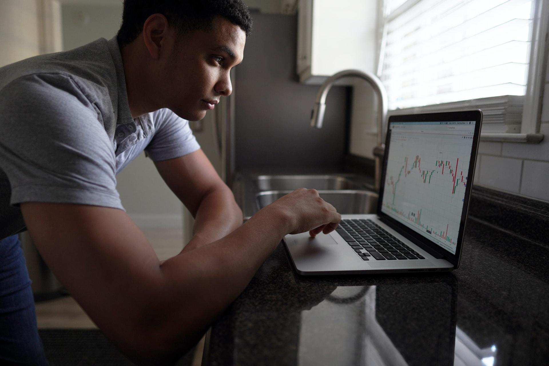 A man in a grey t-shirt using a laptop computer.