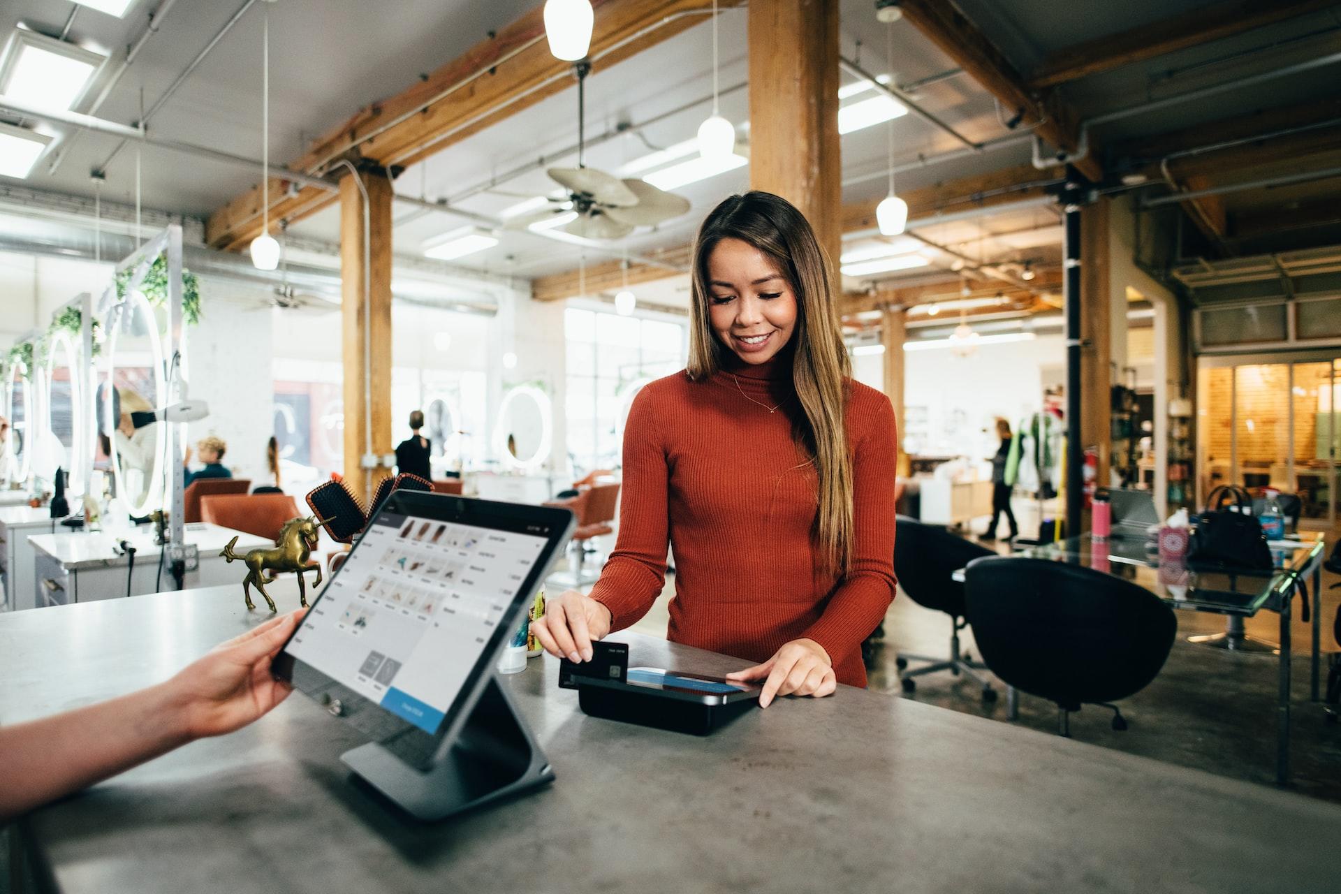 A woman in a coffee shop swiping her credit card