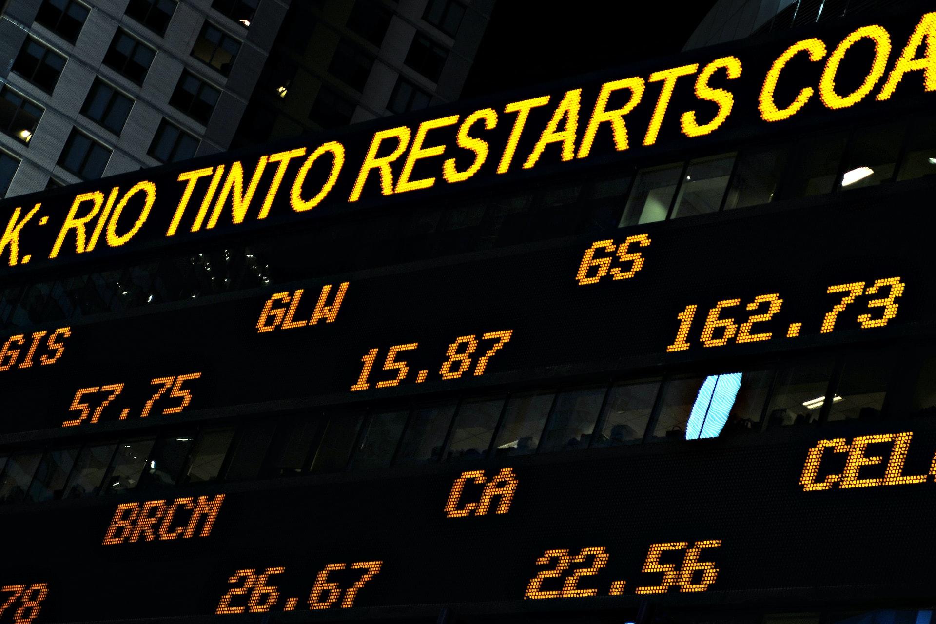 An electronic ticker tape showing stock valuations in orange graphics