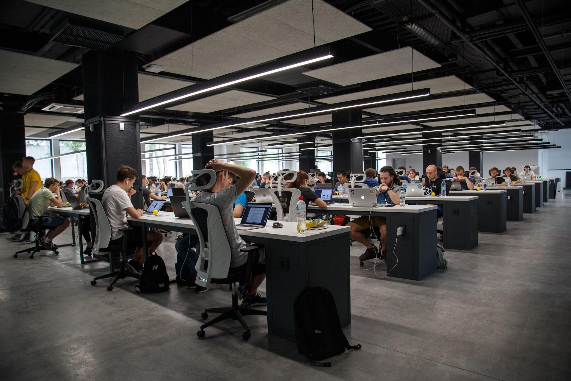 A large room with many desks where employees sit, working on their computers