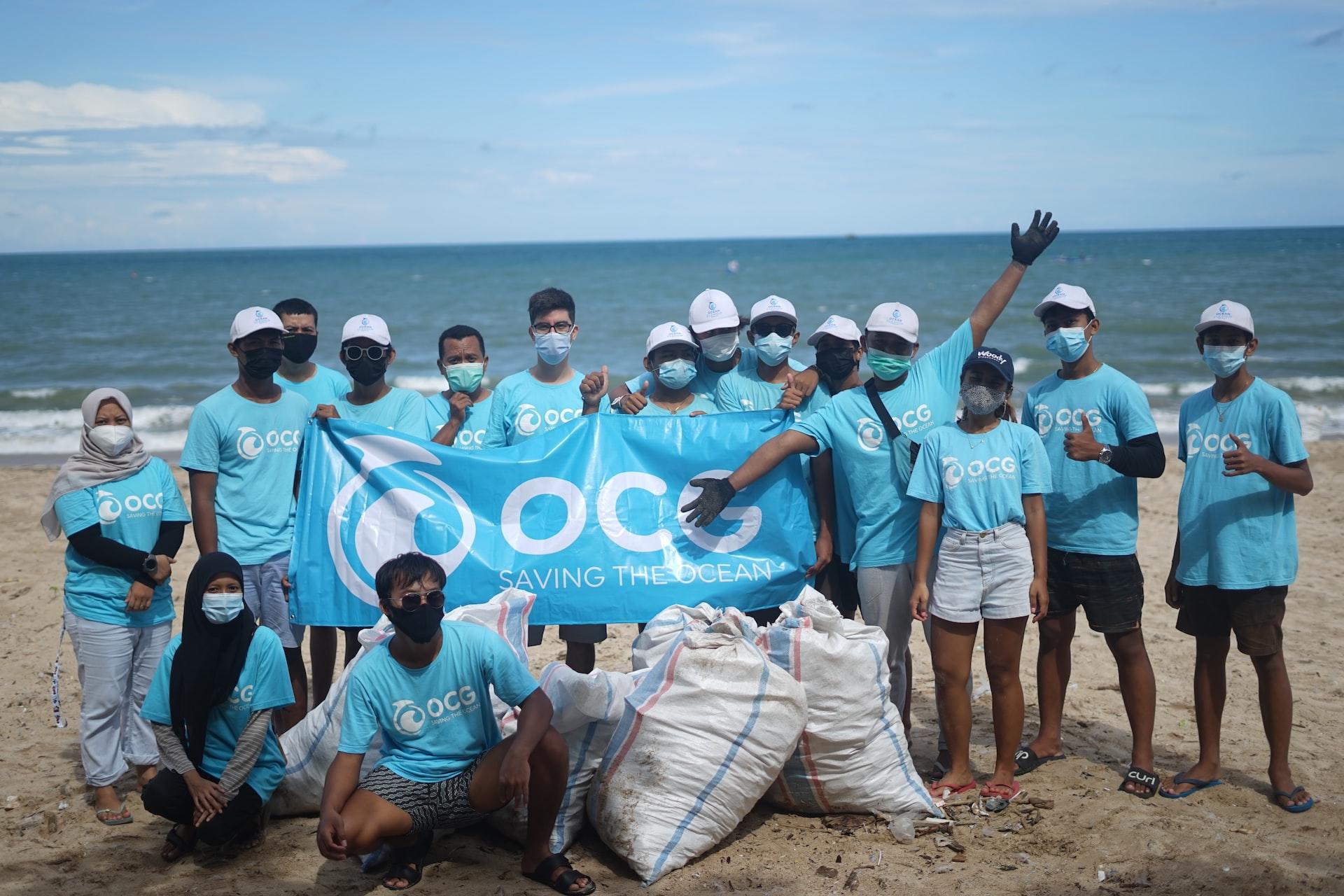 A group of volunteers wearing light blue shirts after cleaning up a beach