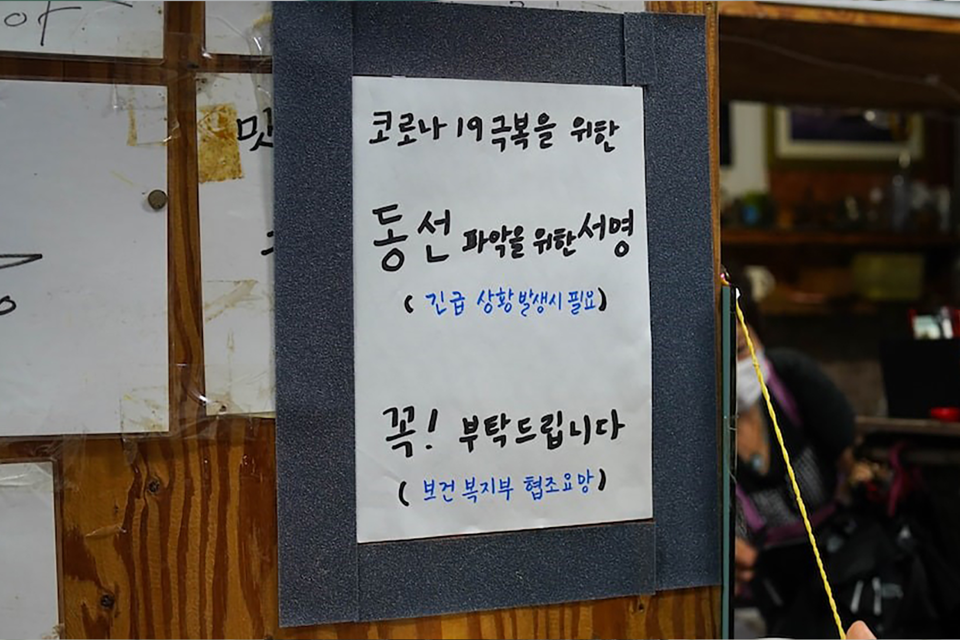 A notice with Korean text pasted on a wooden board