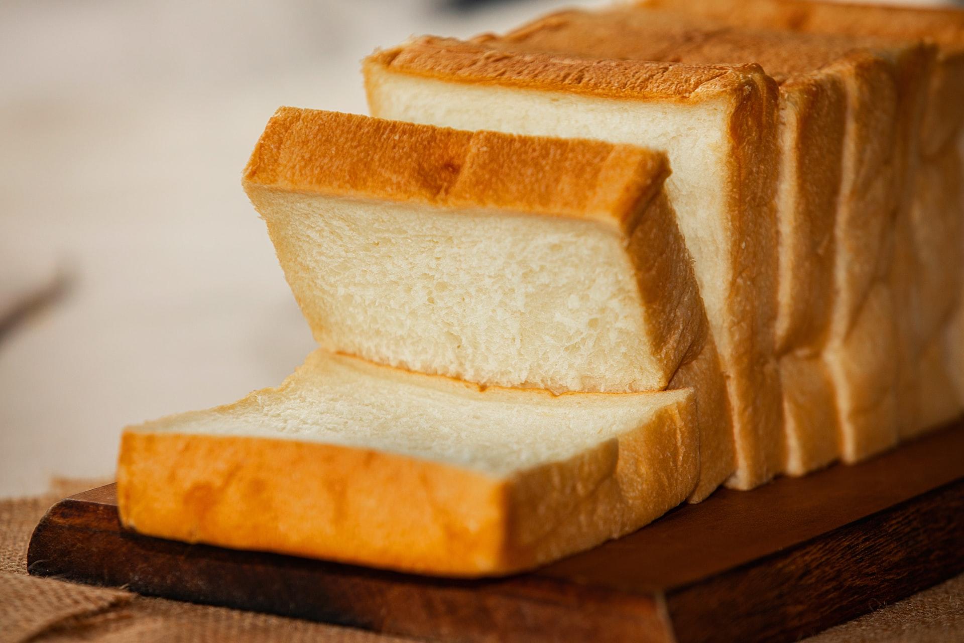 A loaf of sliced white bread on a wooden cutting board