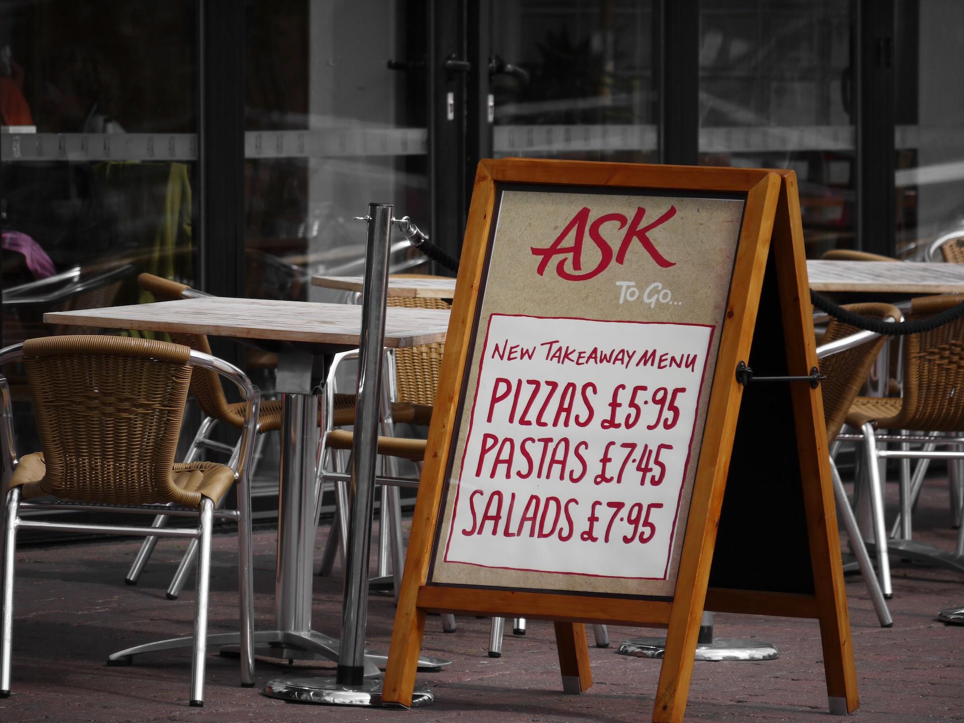 A restaurant sign board listing prices for foods in red ink
