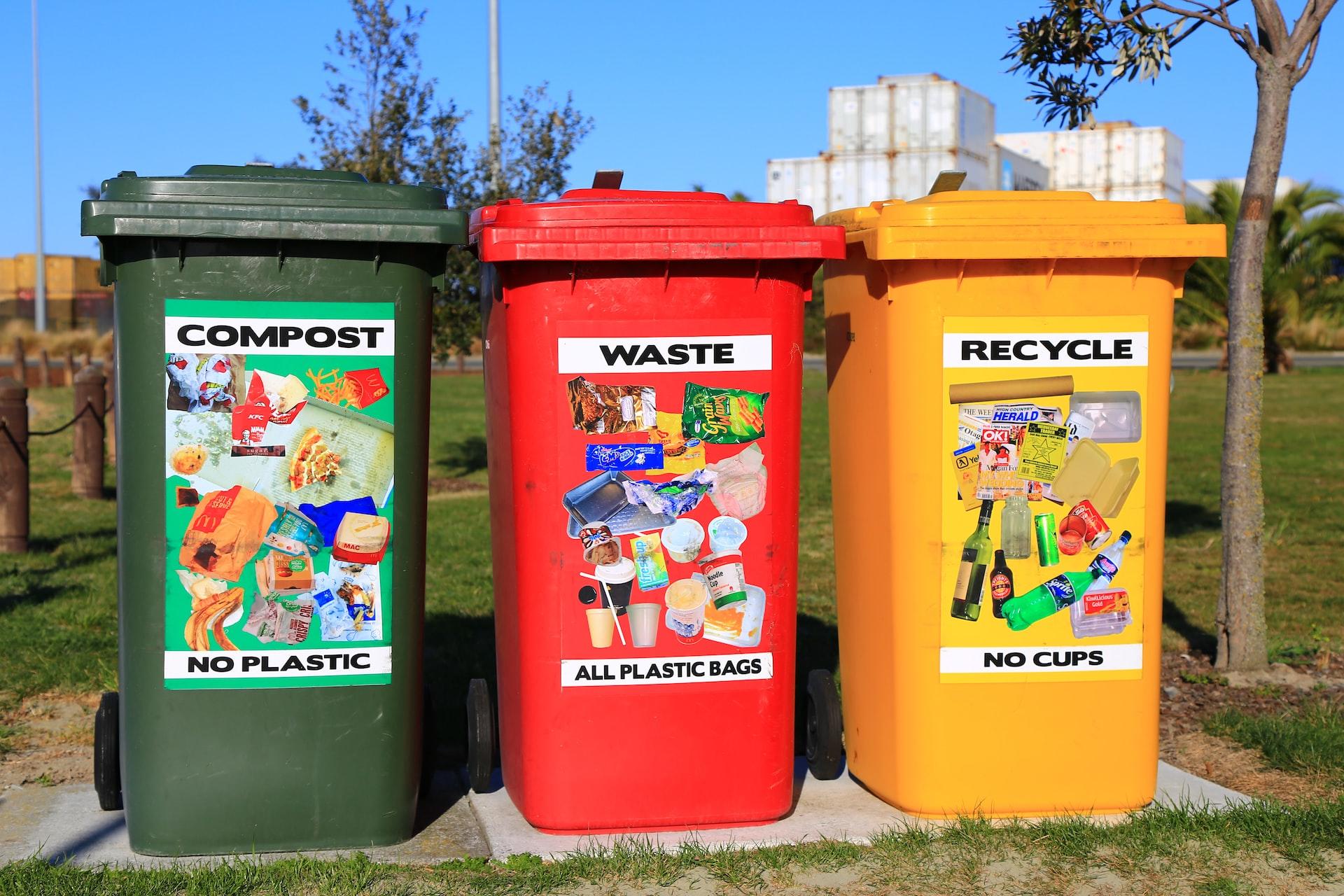 Three wheelie bins, green, red and yellow, for disposing of different types of waste.