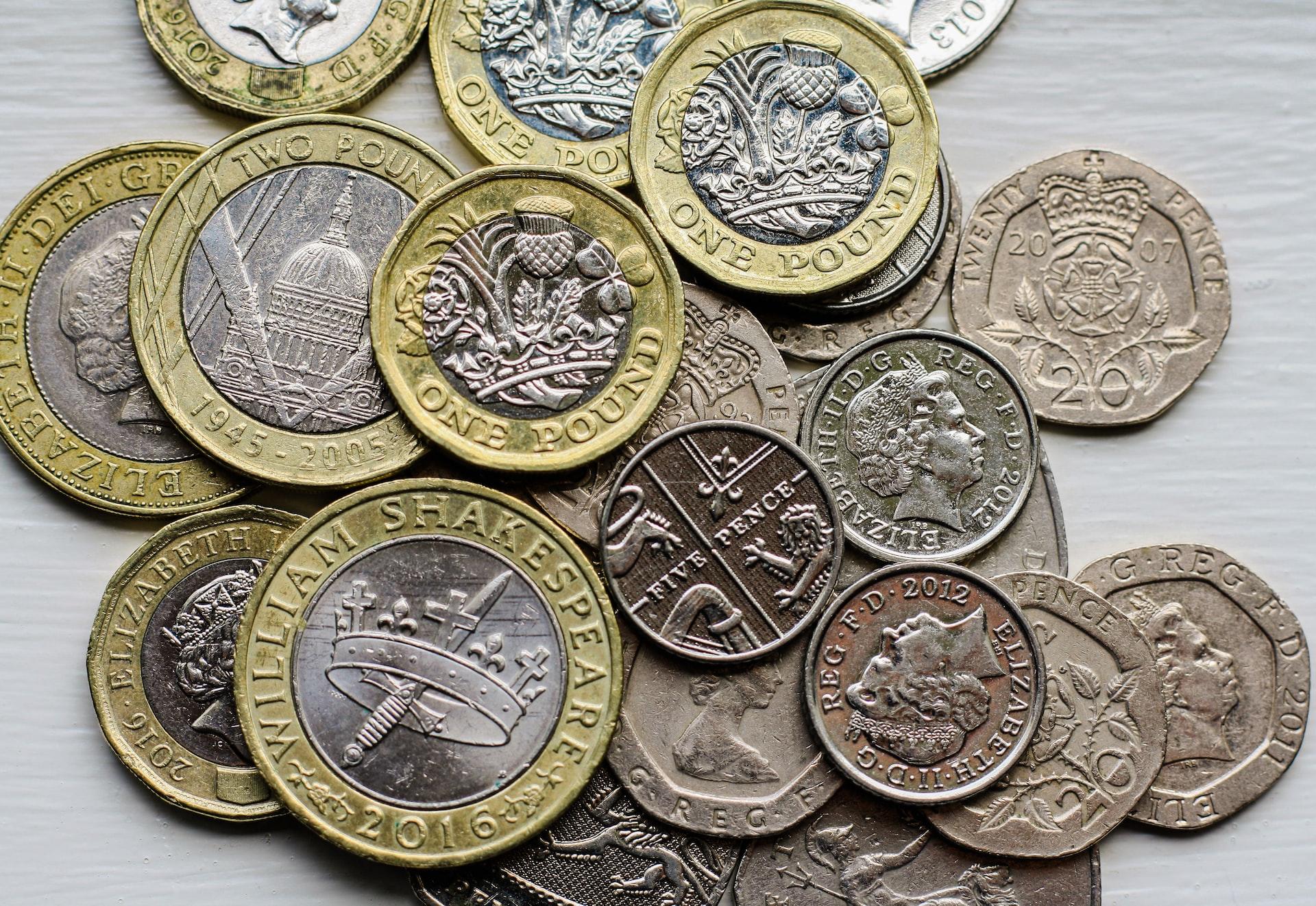 A scattering of GBP coins scattered on a light background.