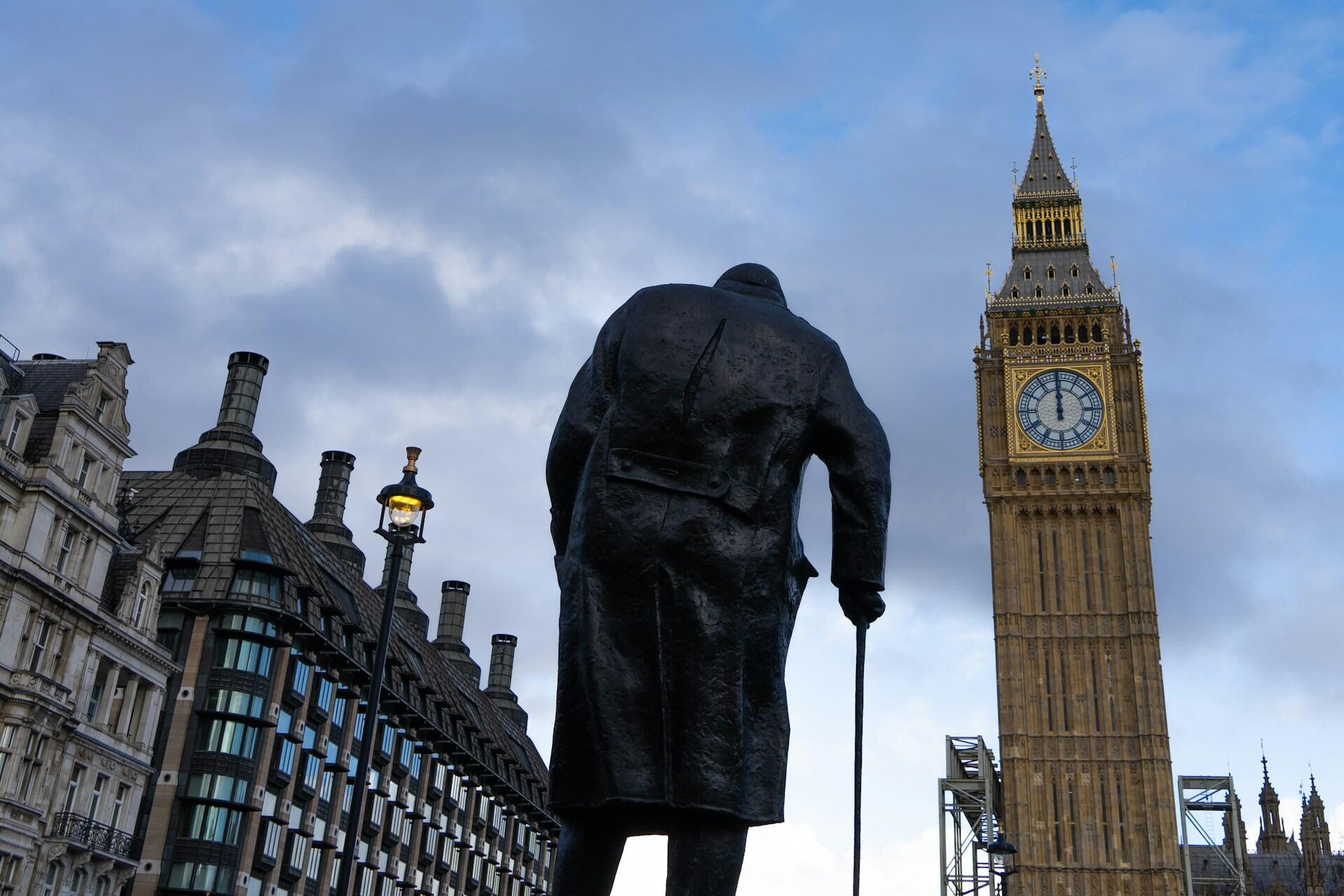 A statue outside of Westminster and Big Ben in London.