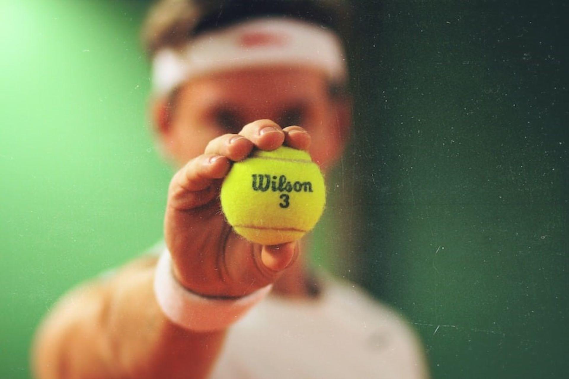 A man is showing a Wilson tennis ball.